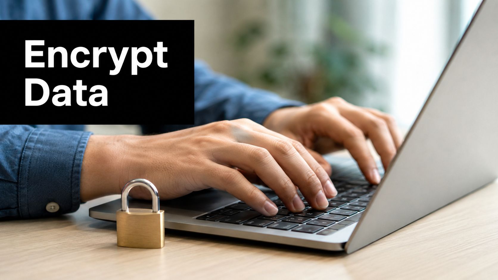 A person typing on a laptop with a gold padlock sitting next to it, representing data security.