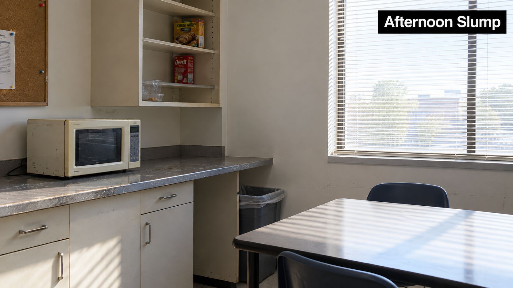A quiet office breakroom featuring a microwave on the counter, shelves with snacks, and a table.