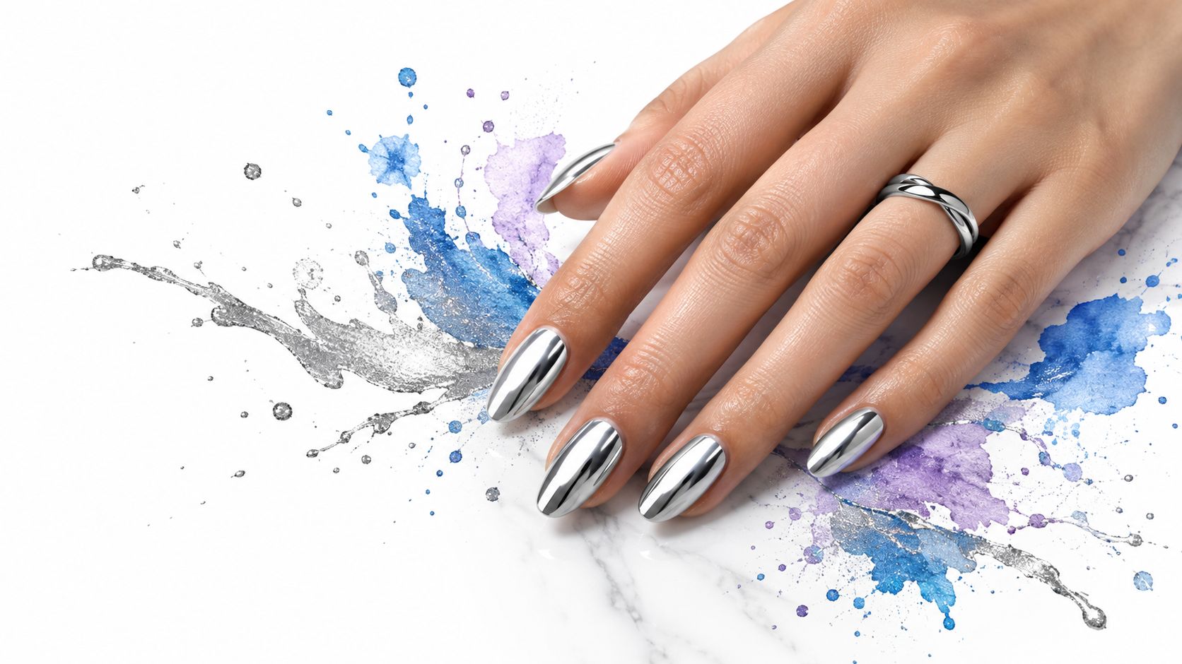 A close-up of a hand with metallic silver nails posing against a background of watercolor splashes.