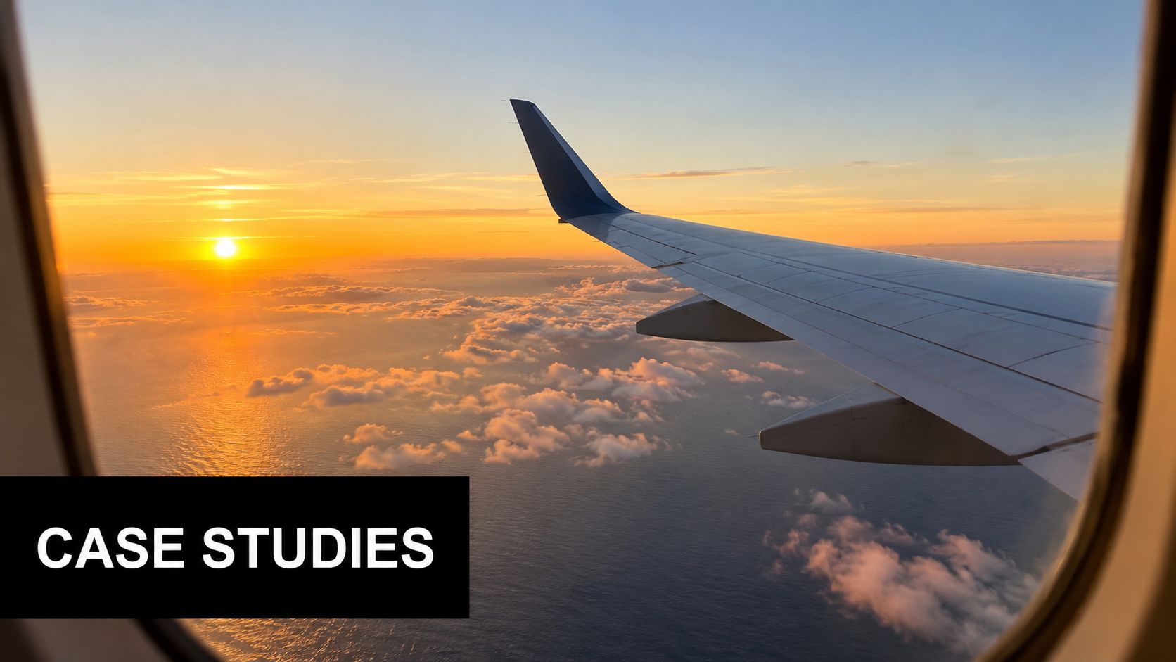 A scenic view of a sunset over the ocean seen through an airplane window while flying.