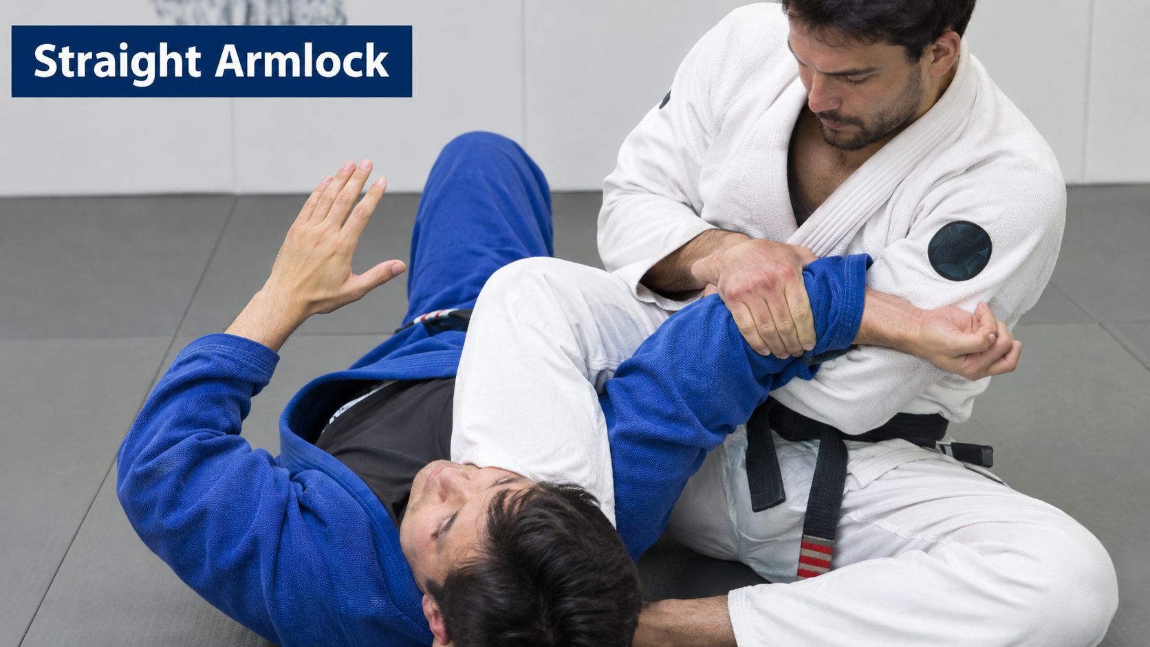 A practitioner in a blue gi applying a straight armlock on an opponent in a white gi.