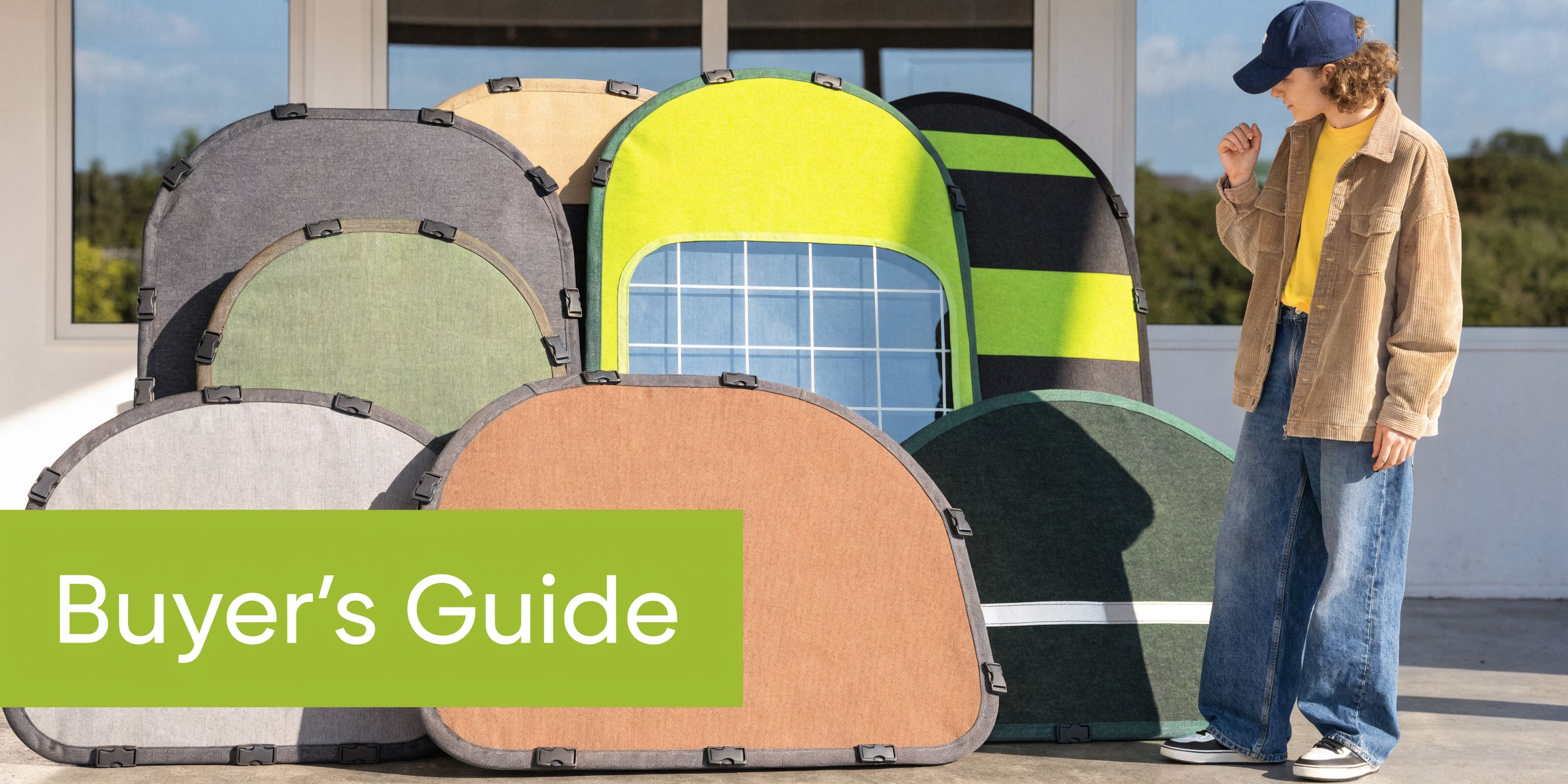 A person standing next to various colors and styles of hard folding tonneau covers for trucks.