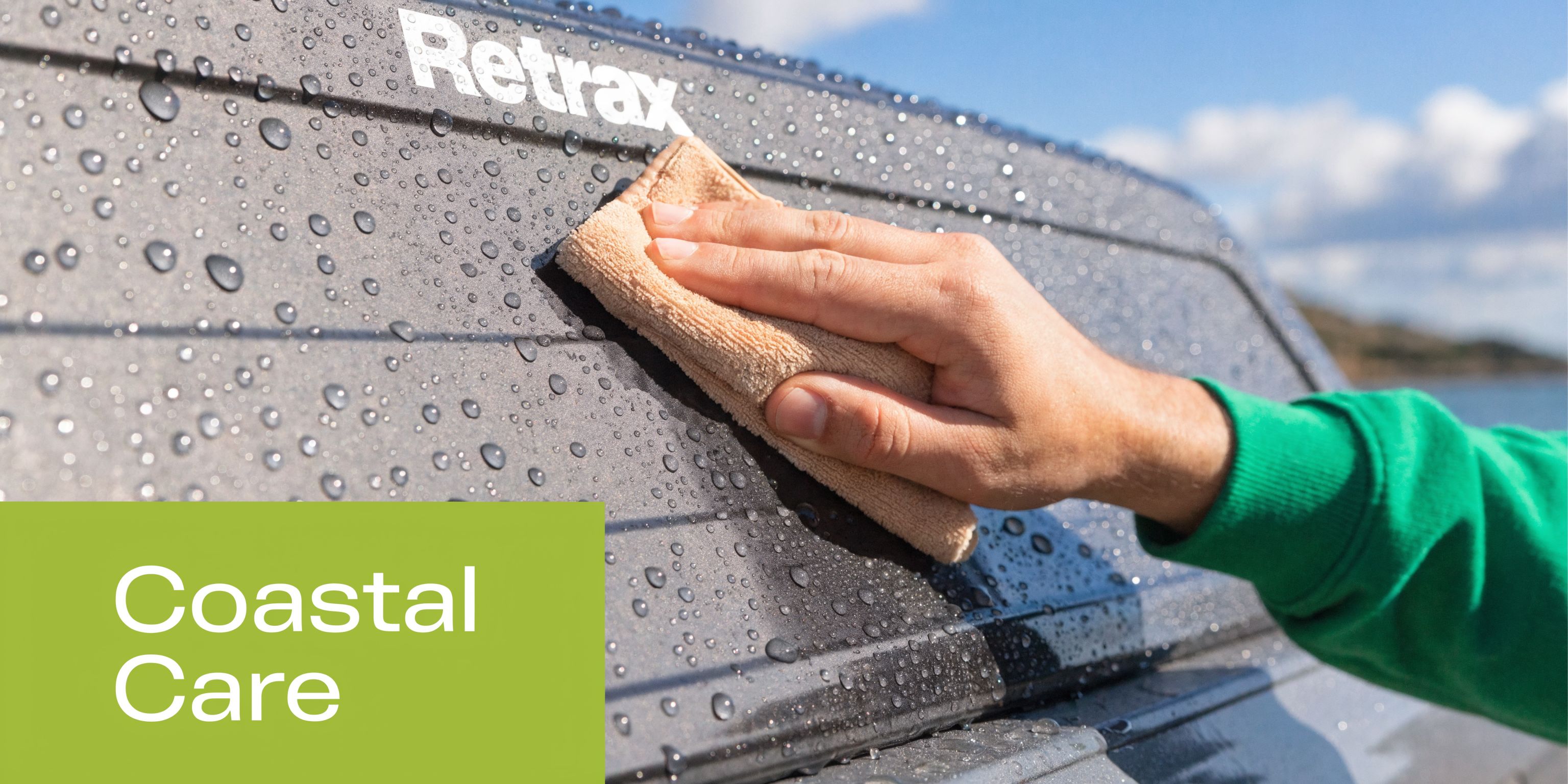 A person wipes a Retrax retractable tonneau cover with a microfiber cloth while water beads on surface.