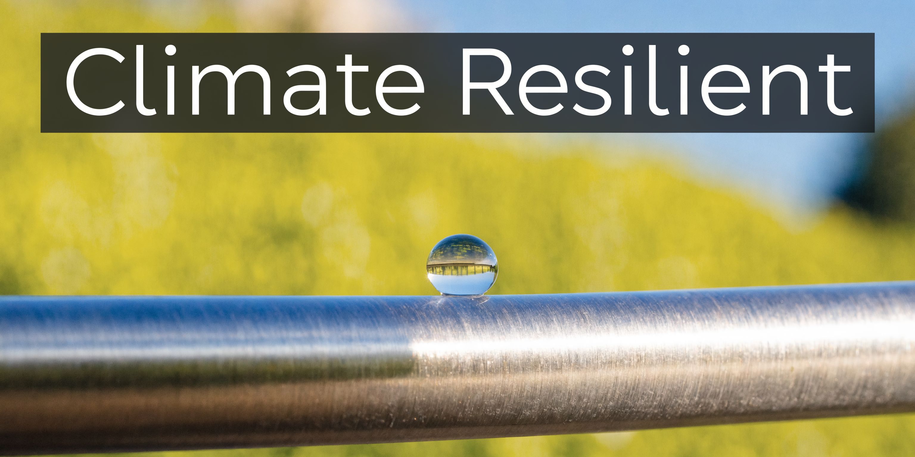 A close up view of a small water drop resting on a metal railing with a blurred field.