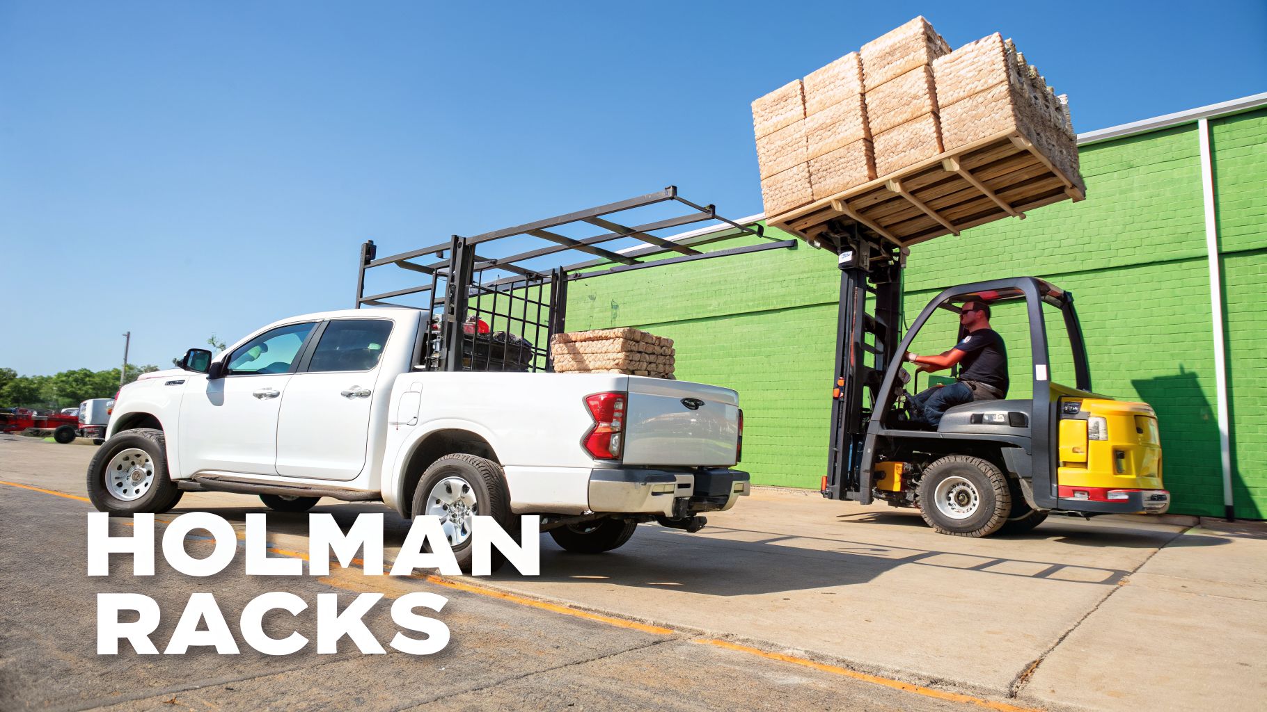 A white pickup truck with a ladder rack is parked next to a forklift loading wooden planks.