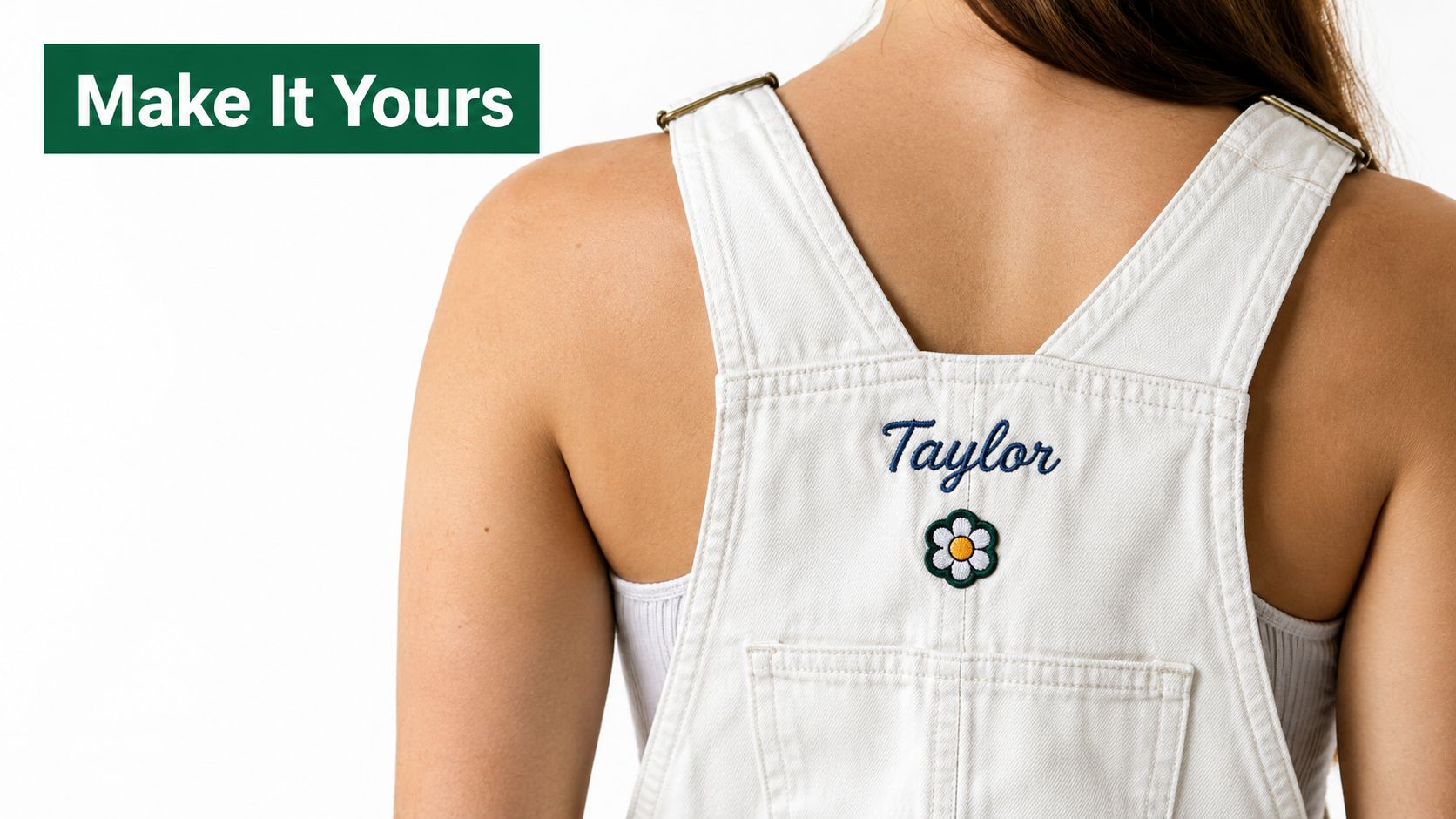 A close-up view of a person wearing white overalls with custom embroidery saying Taylor and a flower.