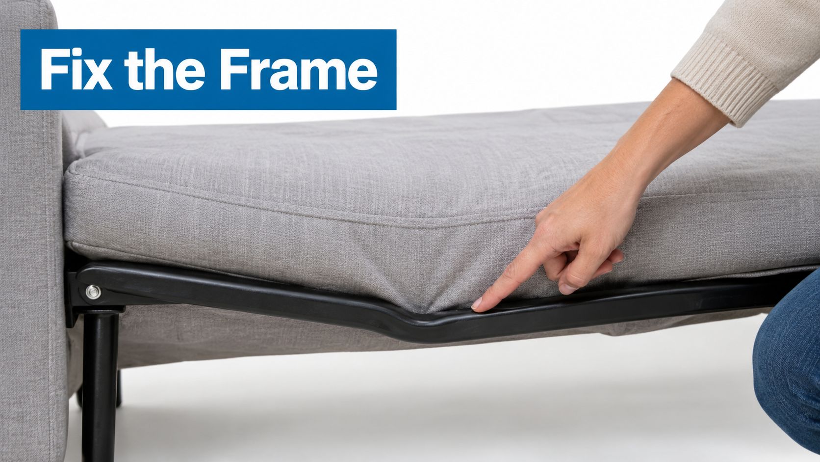 A person pointing at a bent metal frame underneath a grey fabric sofa bed cushion.