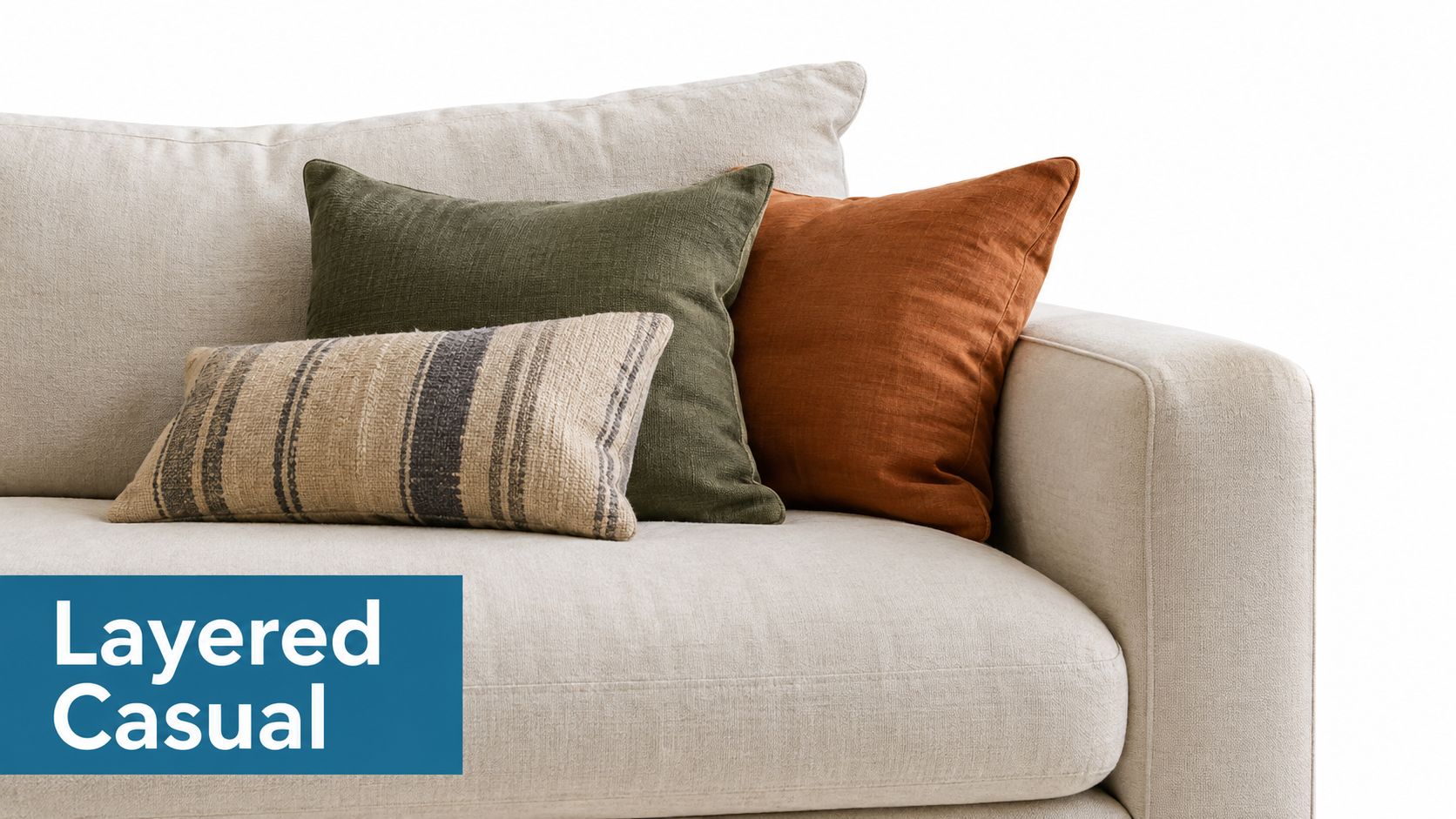 A close up view of a modern cream sofa styled with three decorative pillows in earthy tones.