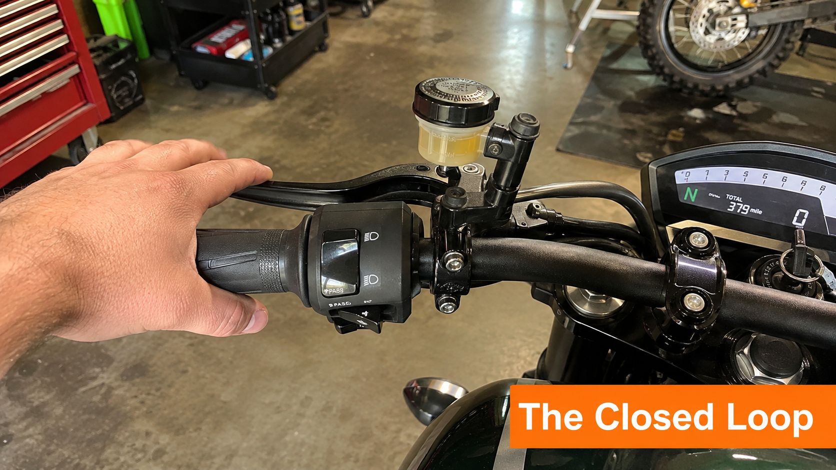 A close-up view of a motorcycle left handlebar assembly with a brake fluid reservoir and switchgear.