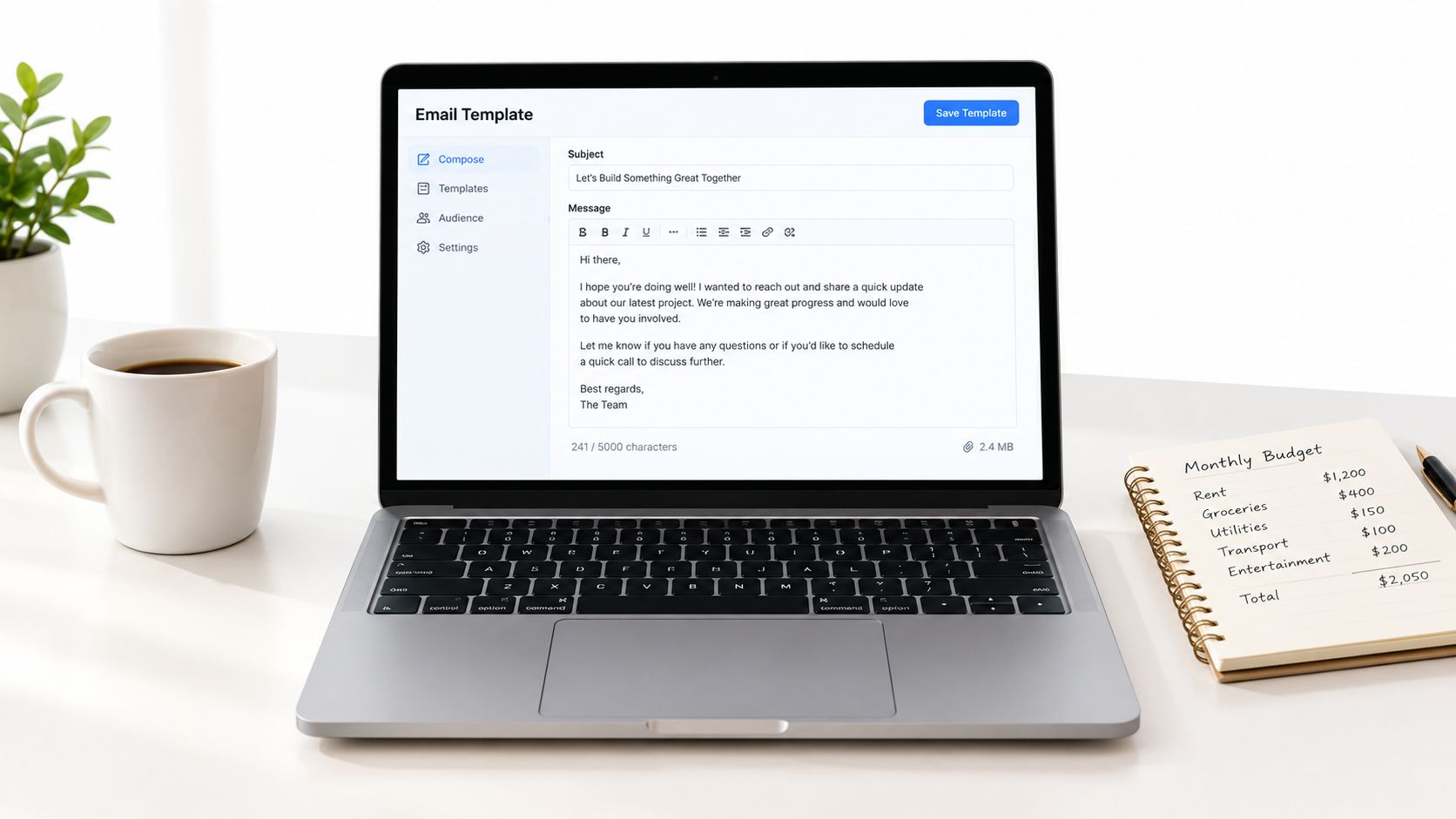 A modern laptop on a desk showing an email composition interface with a budget notebook nearby.