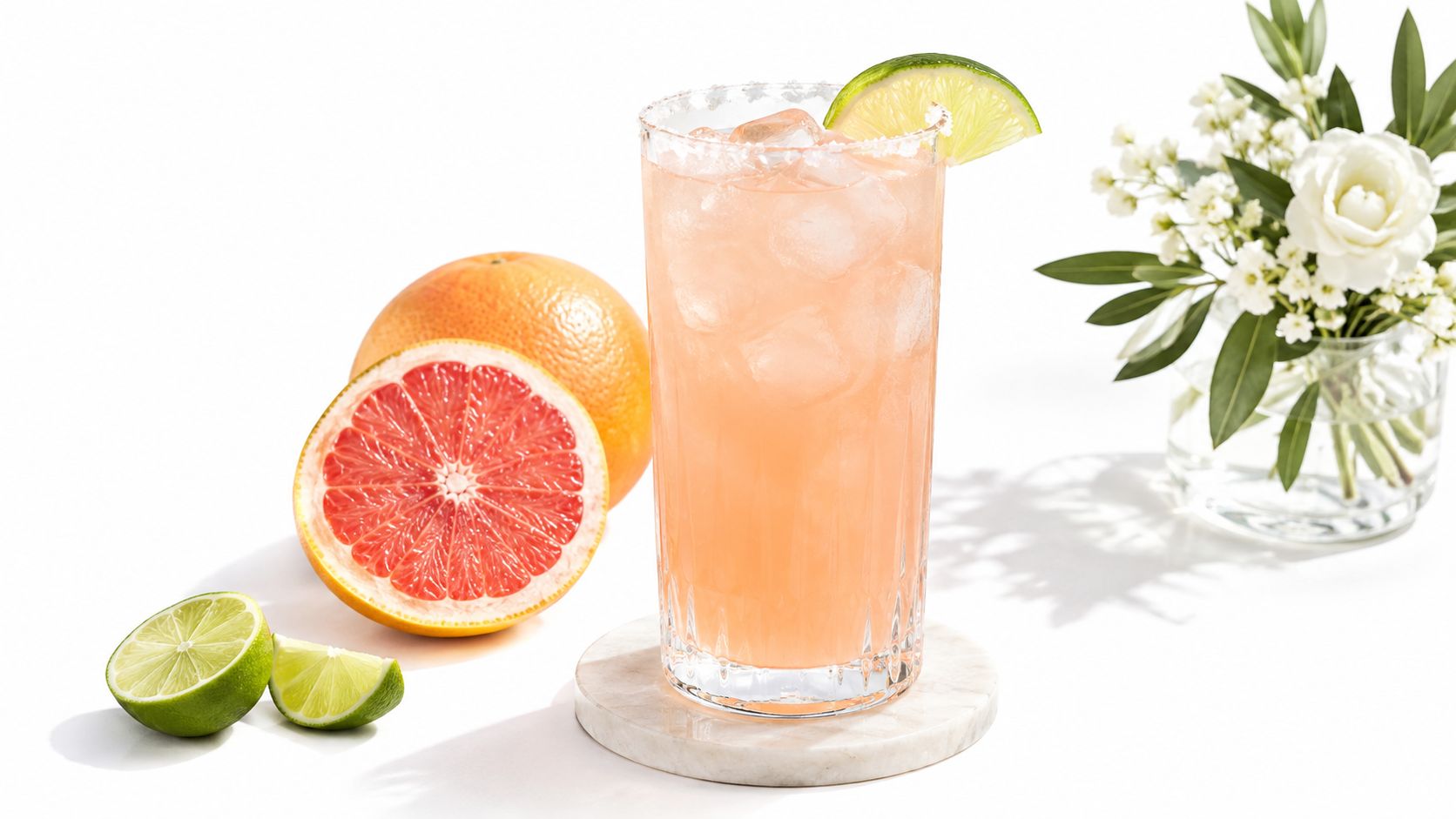 A grapefruit cocktail in a tall glass with a lime wedge.