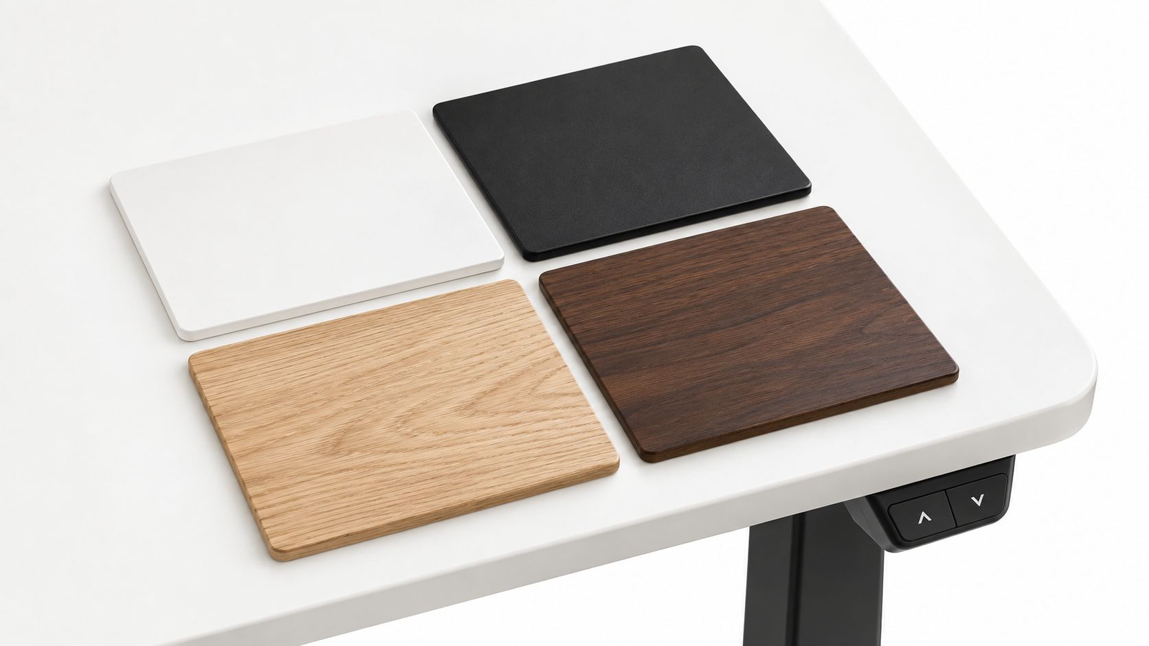 Vier quadratische Musterplatten aus verschiedenen Materialien liegen ordentlich auf einem modernen weißen höhenverstellbaren Schreibtisch angeordnet.