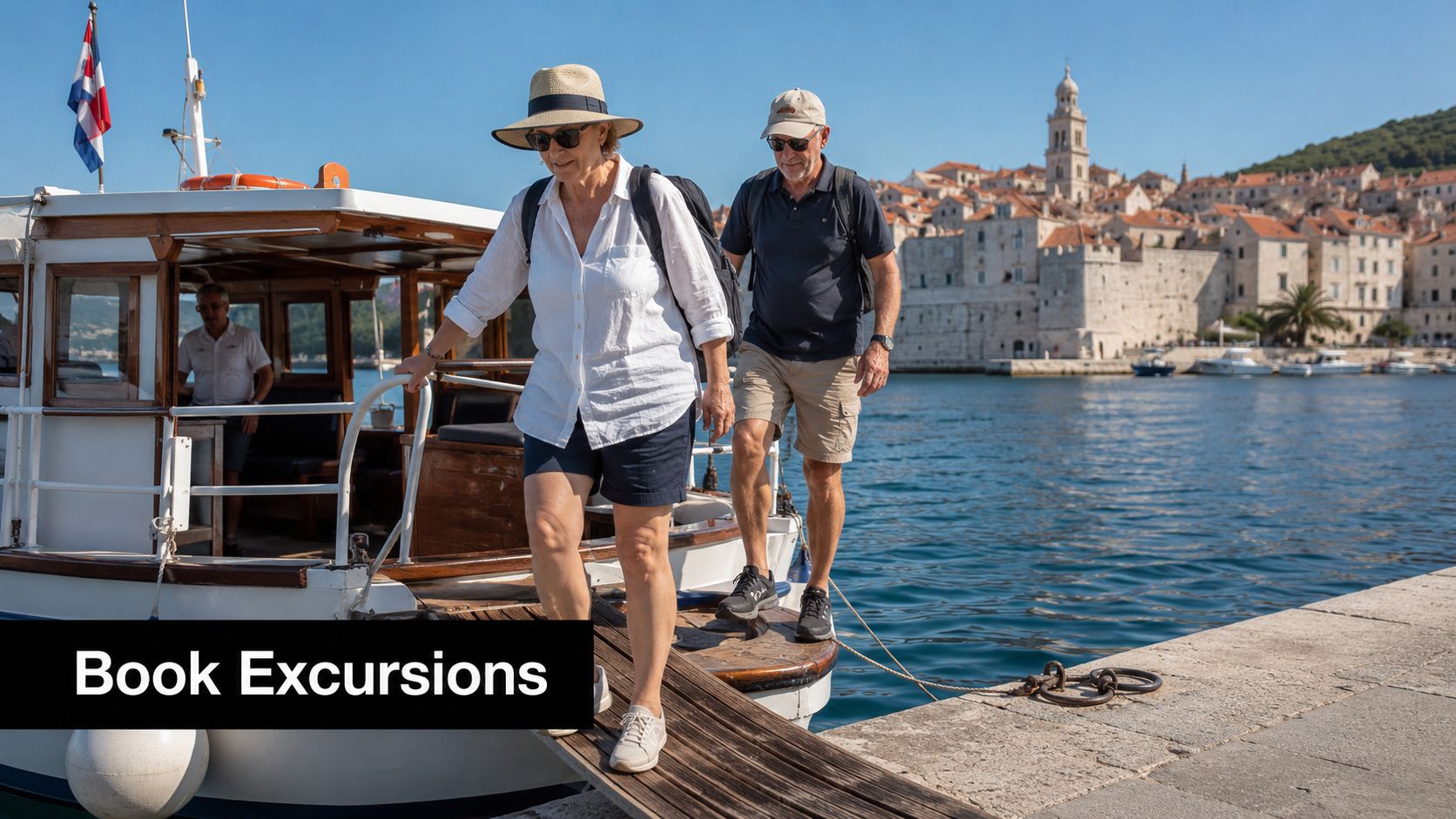 A senior couple disembarks from a boat onto a stone pier in a sunny coastal town.