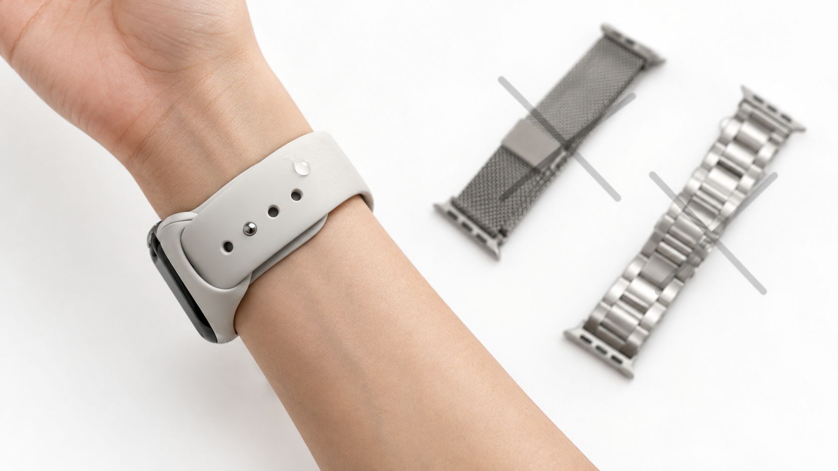A person wearing a silicone watch band, with a metallic mesh and metal link strap shown nearby.