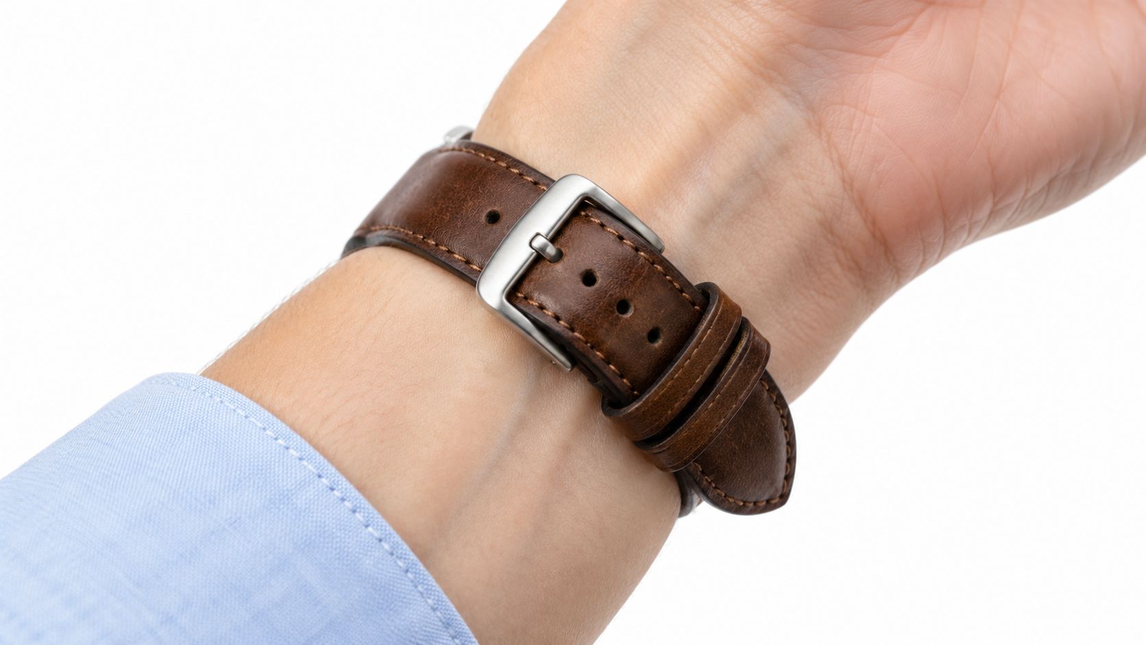 Close up view of a brown leather watch strap fastened securely around a person's wrist.