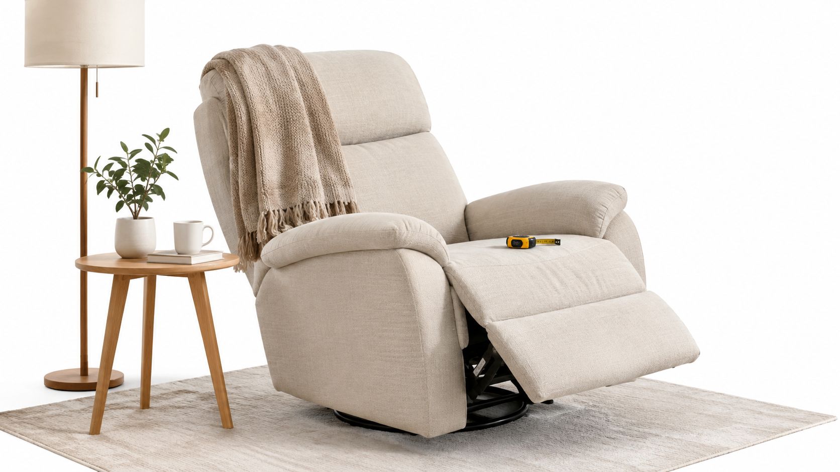 A beige recliner armchair with a cozy throw blanket sitting on a rug next to a side table.