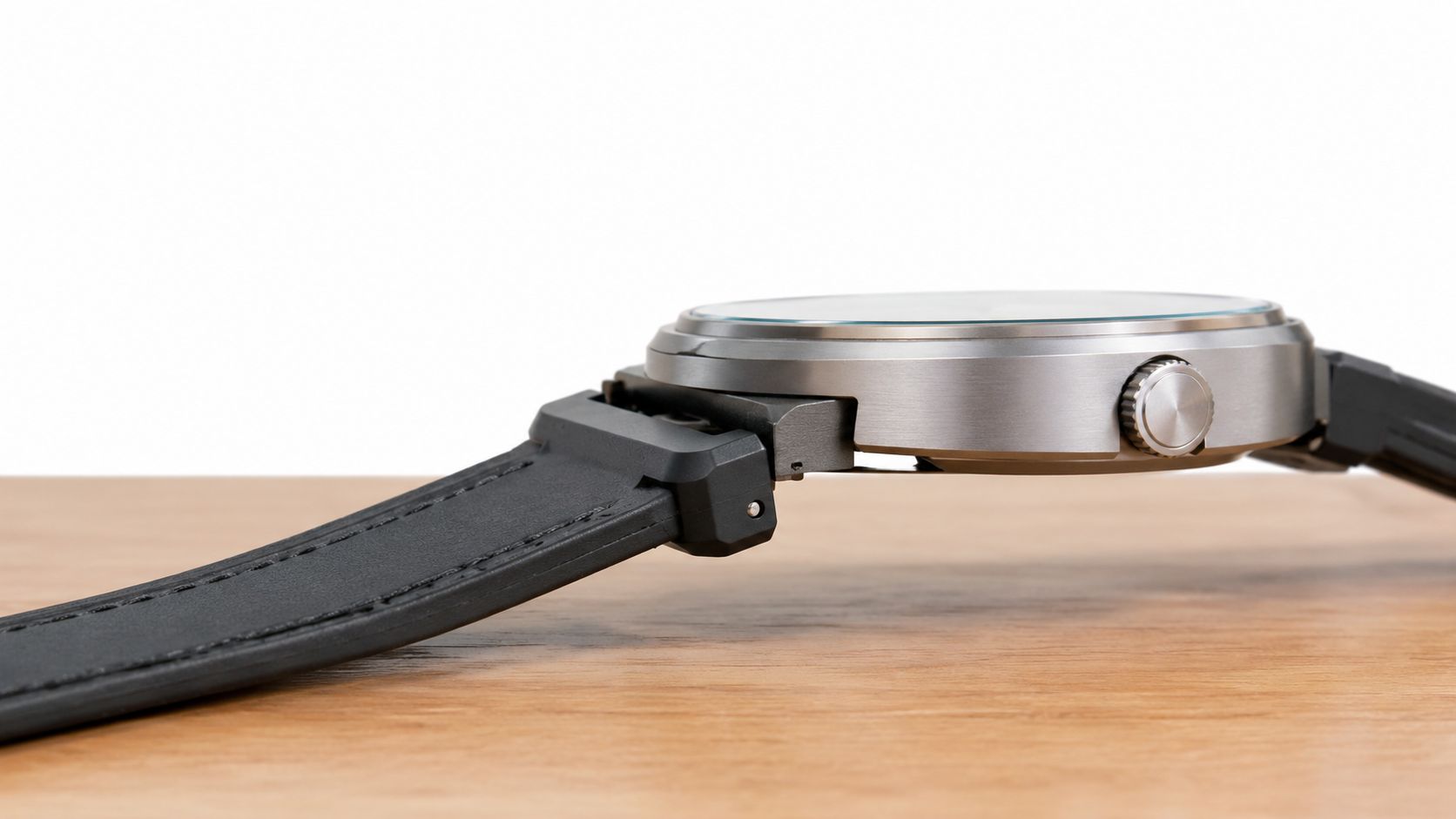 A close-up side view of a wristwatch featuring a black leather strap with a quick release adapter.