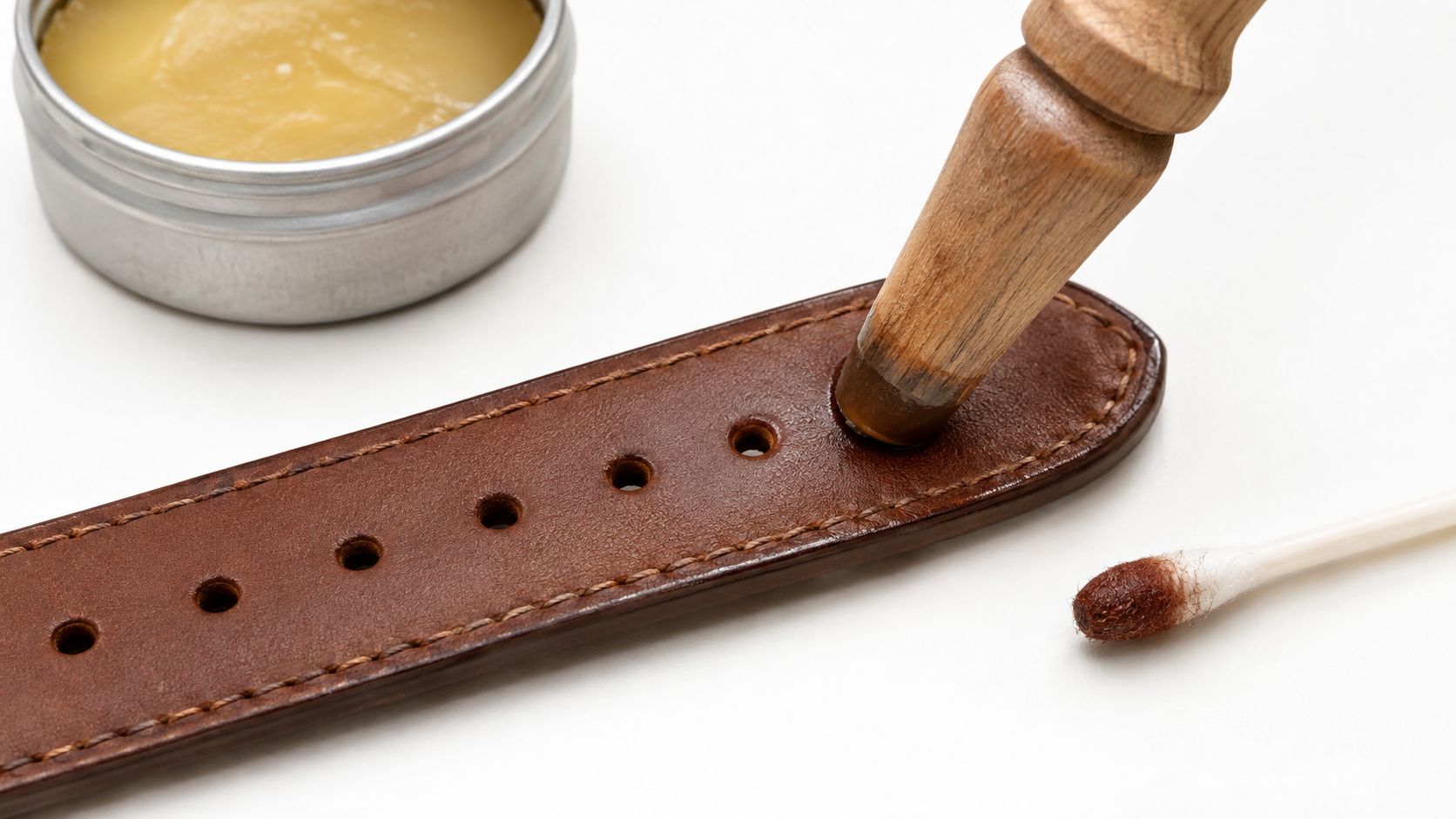 A leather tool used to burnish the edges of a brown leather watch strap on a table.