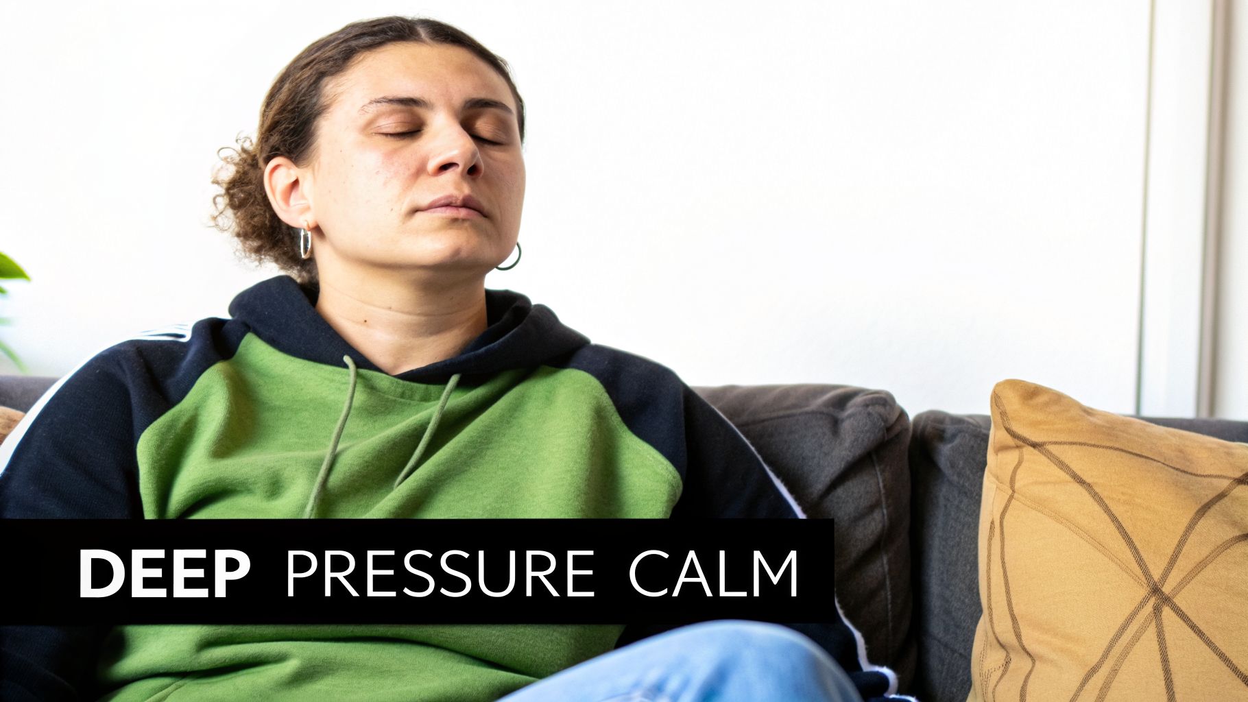 A person with closed eyes sits calmly on a couch, wearing a green hooded sweatshirt.