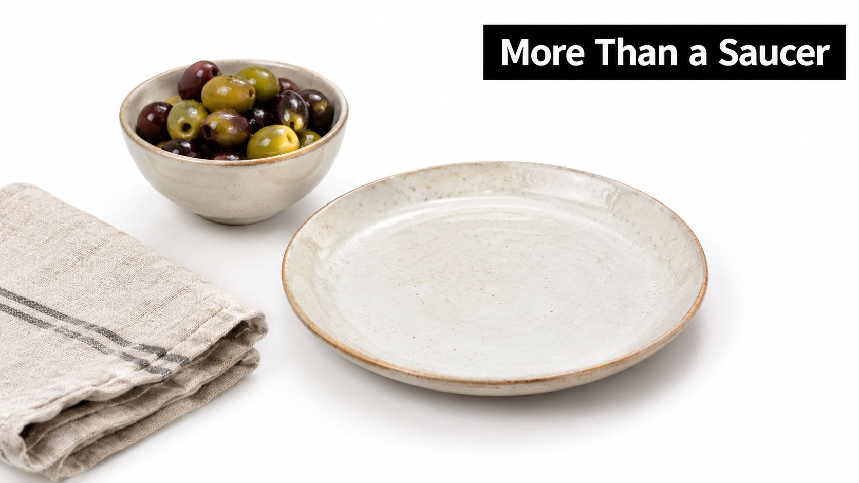 A rustic ceramic side plate sits beside a bowl of assorted olives on a white background.