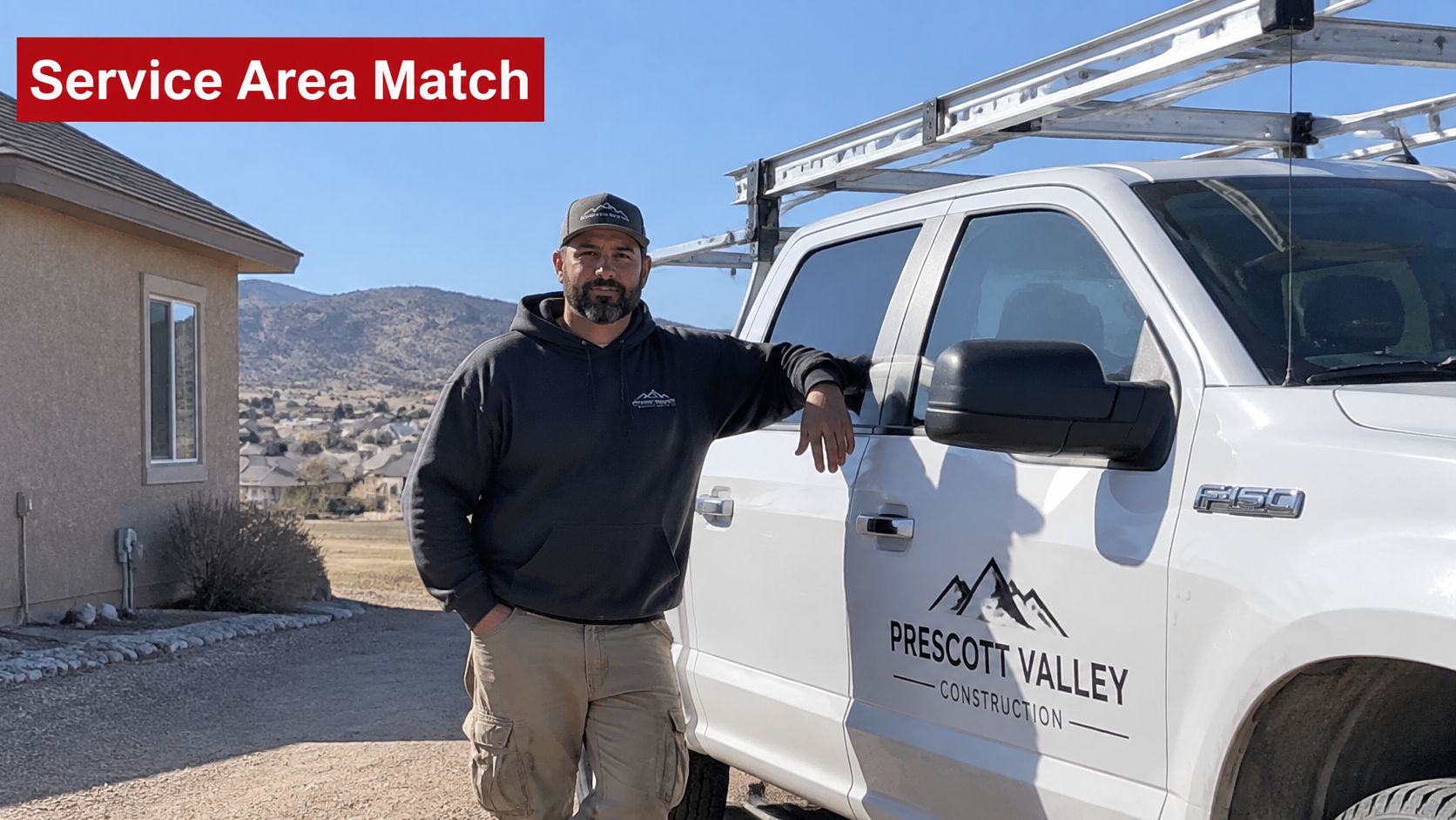 A professional construction contractor standing next to his company truck at a residential job site location.