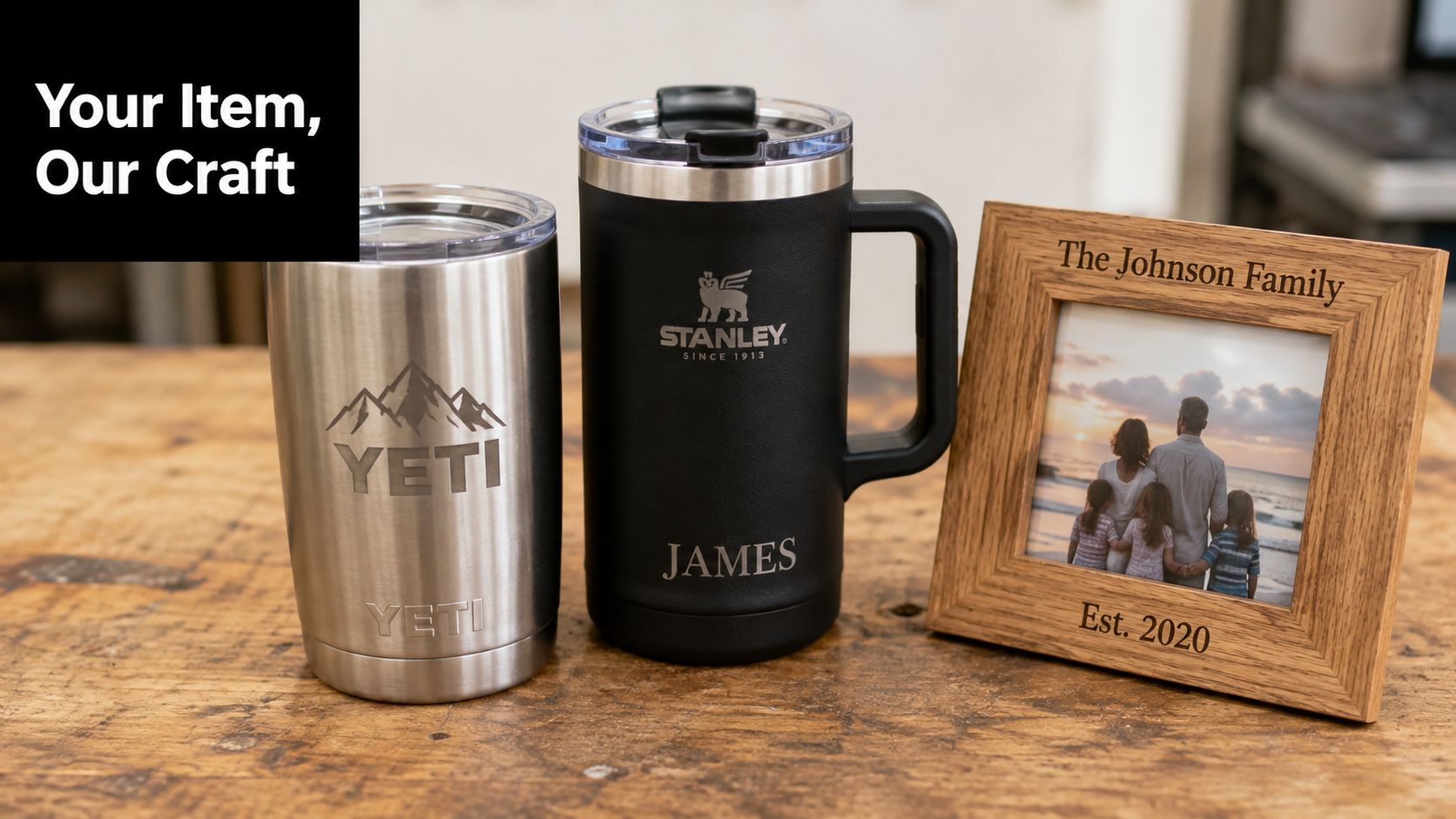 Custom engraved stainless steel tumblers and a wooden picture frame sitting on a rustic wooden workshop table.