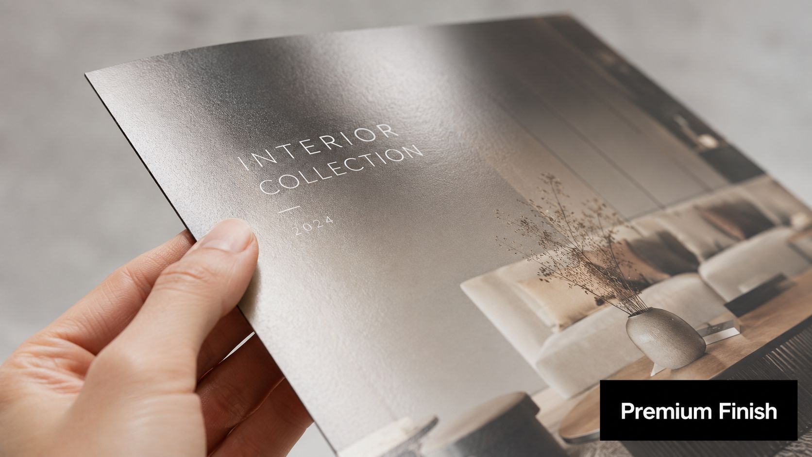 A hand holding a high-quality brochure titled Interior Collection 2024 with a premium finish texture.