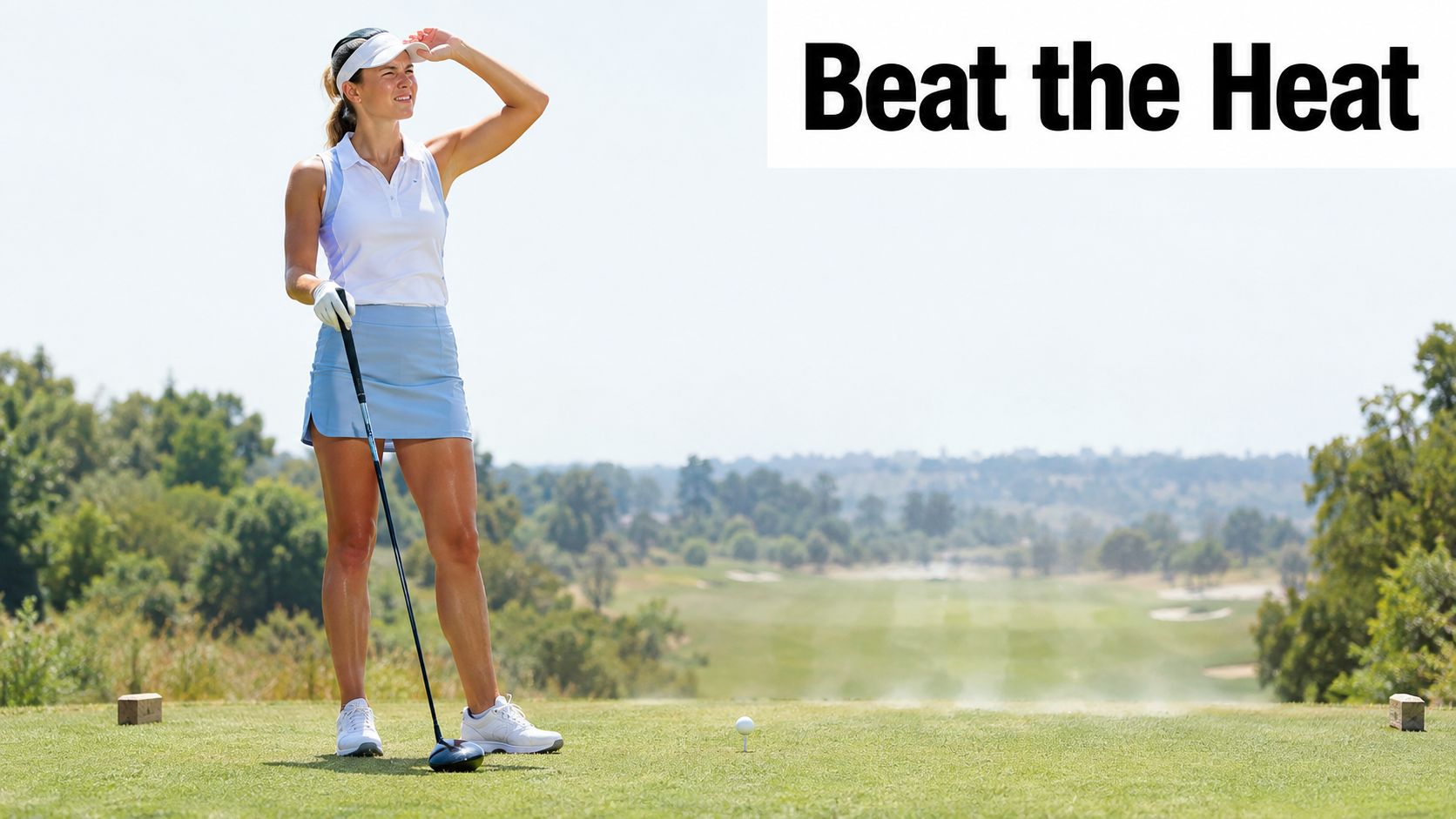 A female golfer standing on a sunny golf course tee box wearing a visor and athletic apparel.