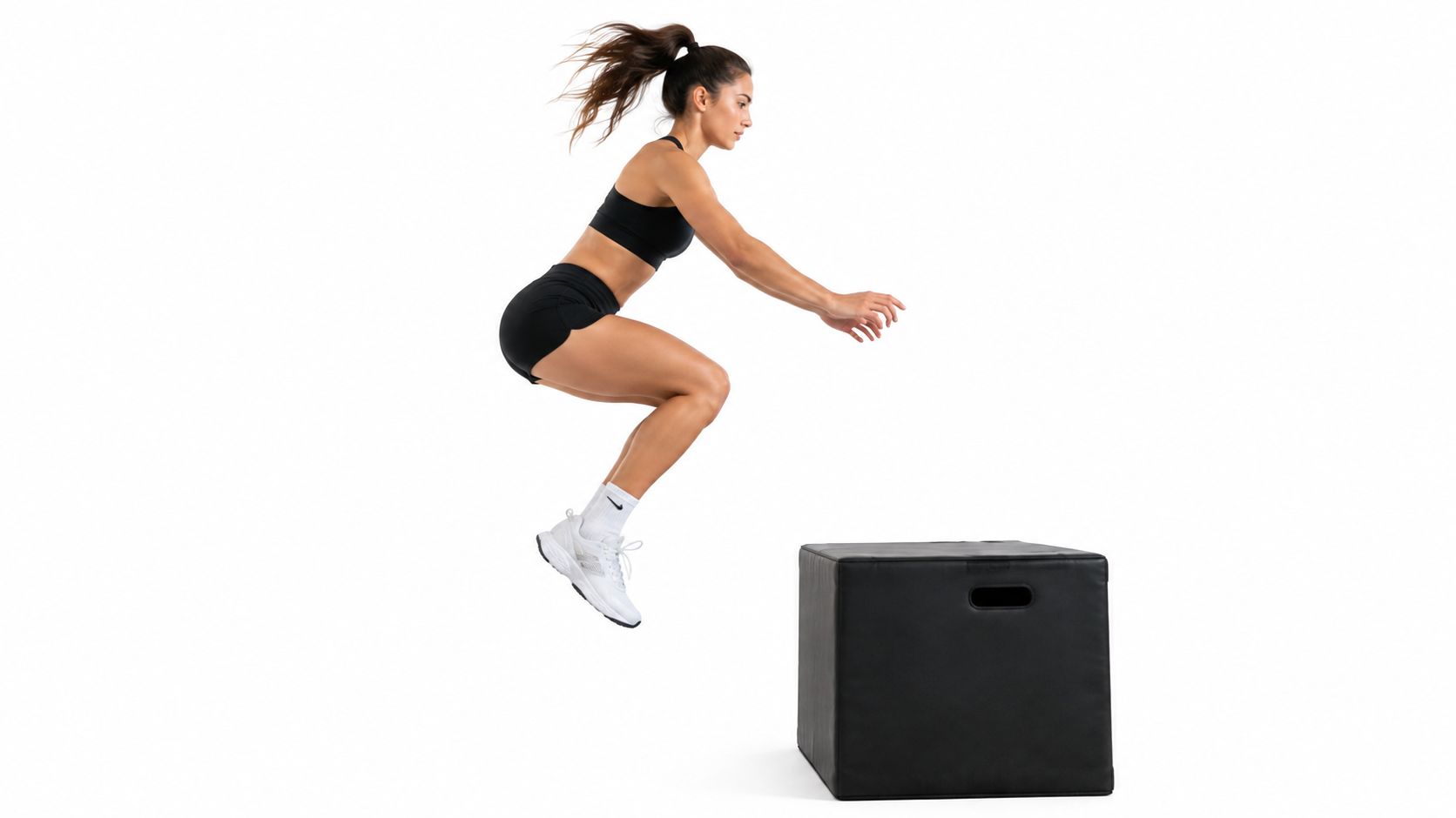 A fit woman in athletic wear performing a powerful vertical box jump in a studio setting.