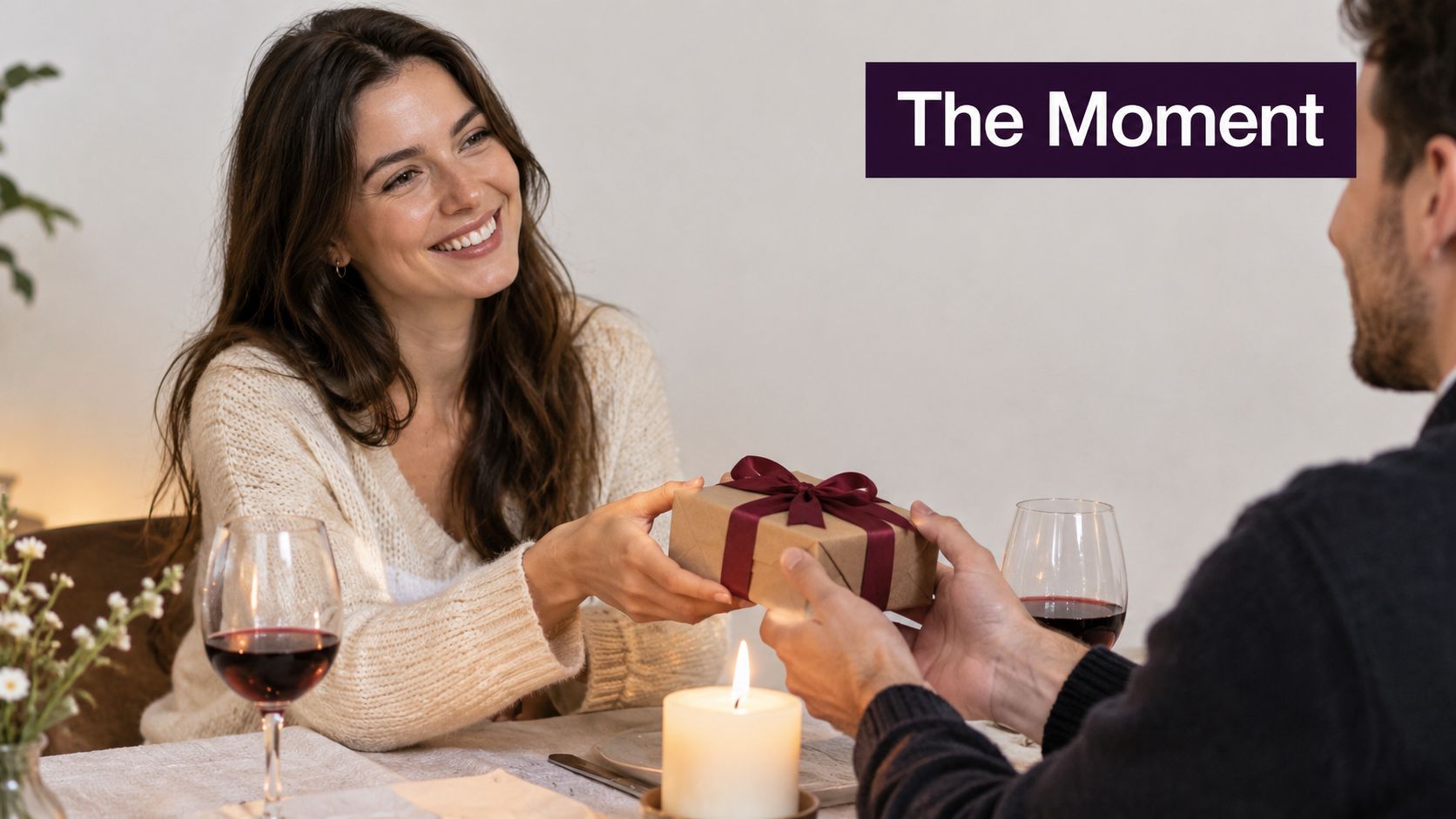 A woman smiling as she receives a beautifully wrapped gift from her partner during dinner.