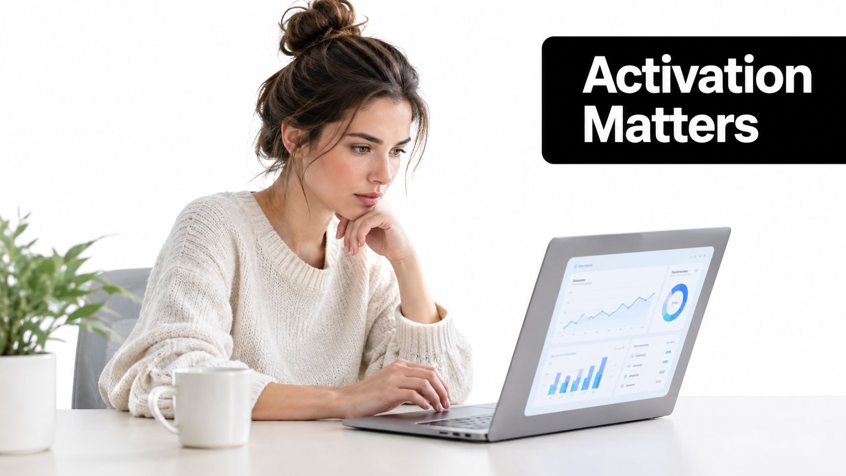 A woman in a cozy sweater working on a laptop displaying data analytics charts at a desk.