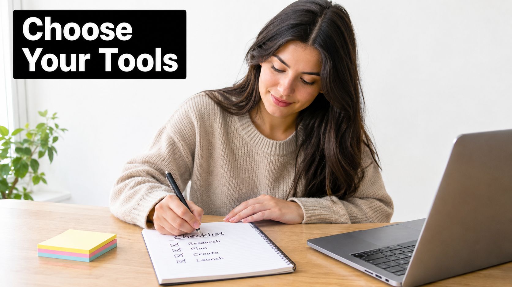 A woman smiles while writing a productivity checklist in a notebook at her desk with a laptop.
