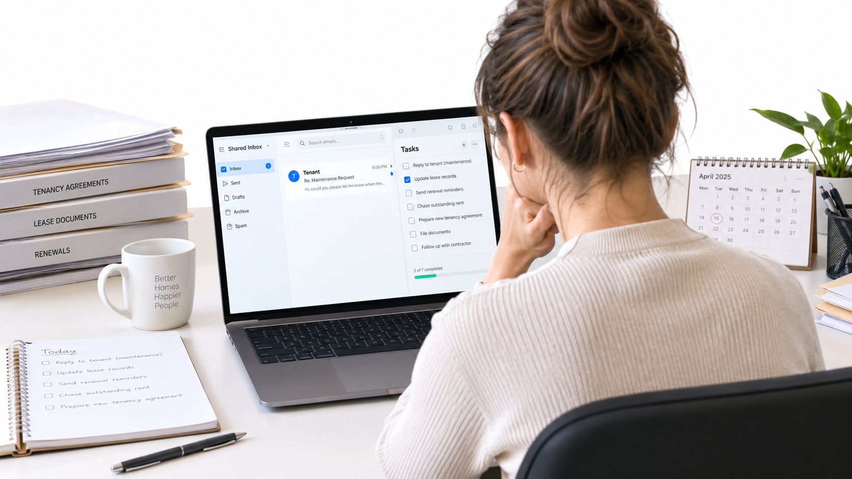 A professional working at a desk with a laptop displaying lease management software and organized paperwork.