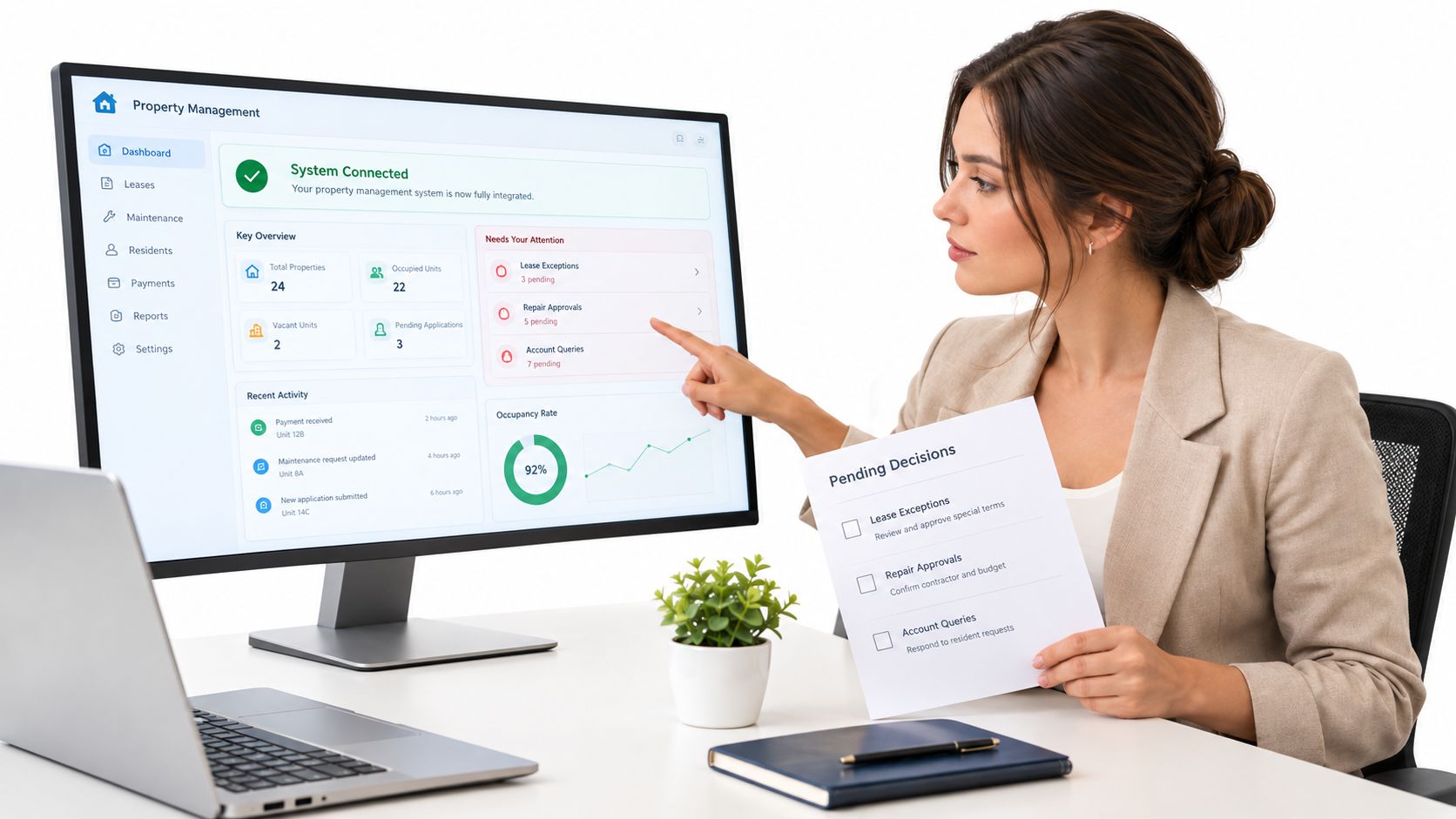 A professional woman in a blazer pointing at a property management software dashboard on a computer monitor.