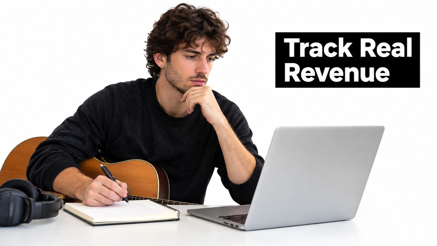 A focused young musician writing in a notebook while looking at his laptop screen for tracking sales.