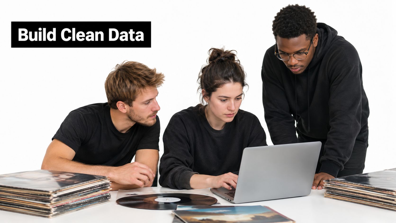 A diverse group of young adults working together on a laptop while surrounded by vinyl records.