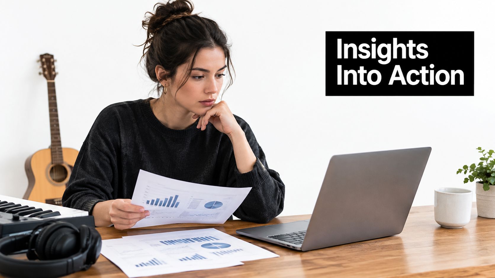 A young woman sits at a desk analyzing business charts while working on her laptop computer.