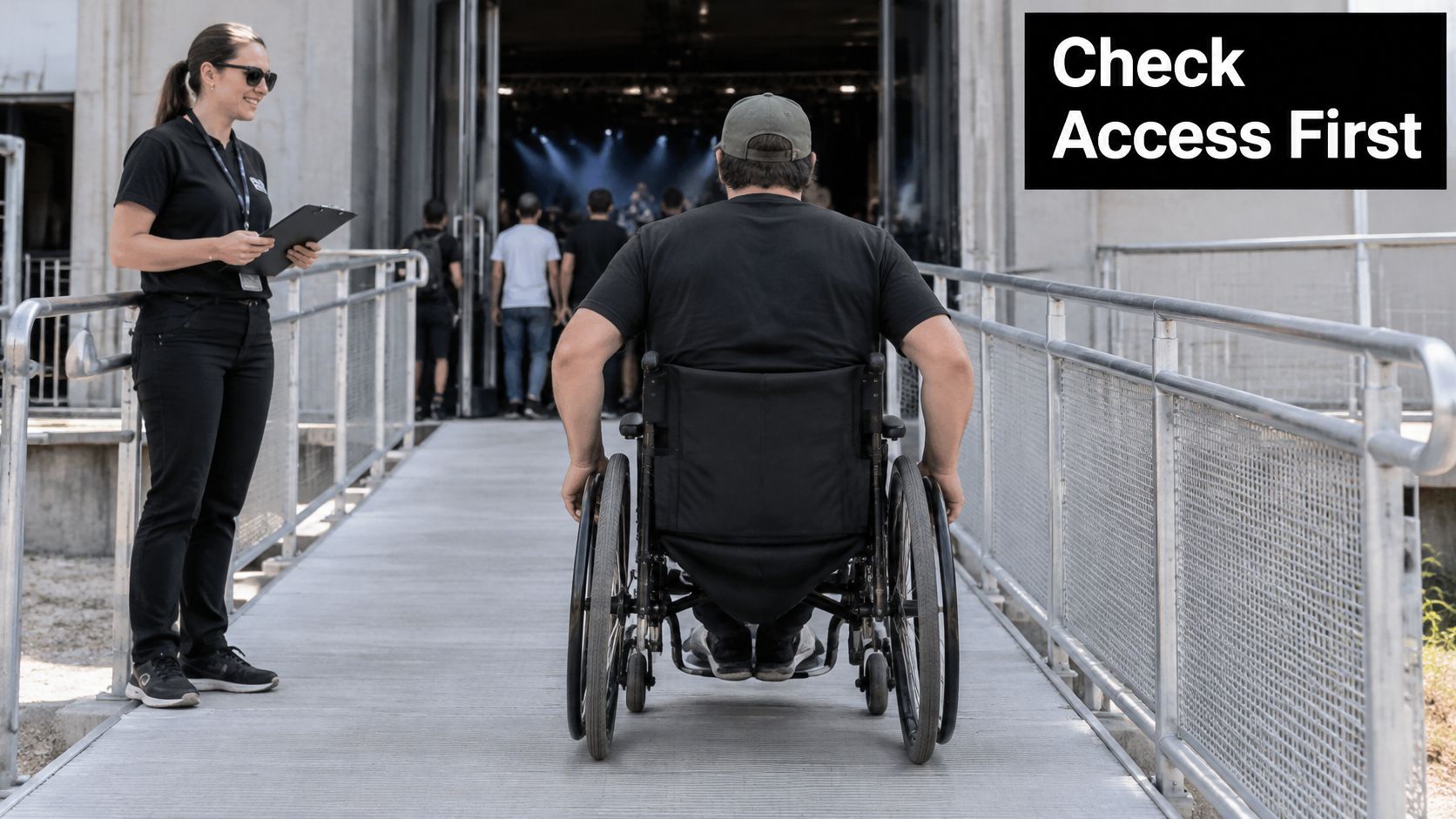 A staff member checks a person in a wheelchair entering a music event venue via a ramp.