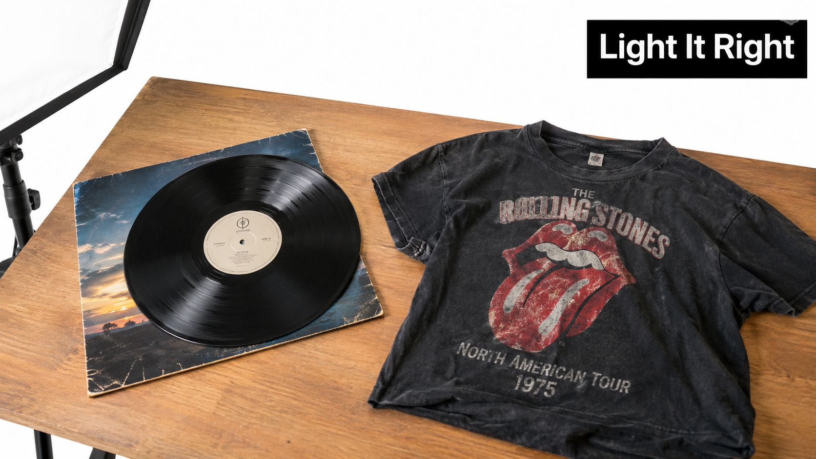 A Rolling Stones 1975 tour t-shirt and a vintage vinyl record displayed on a wooden table.