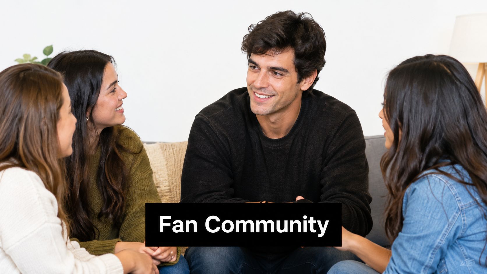 A diverse group of four young friends sitting on a couch laughing and having a conversation together.
