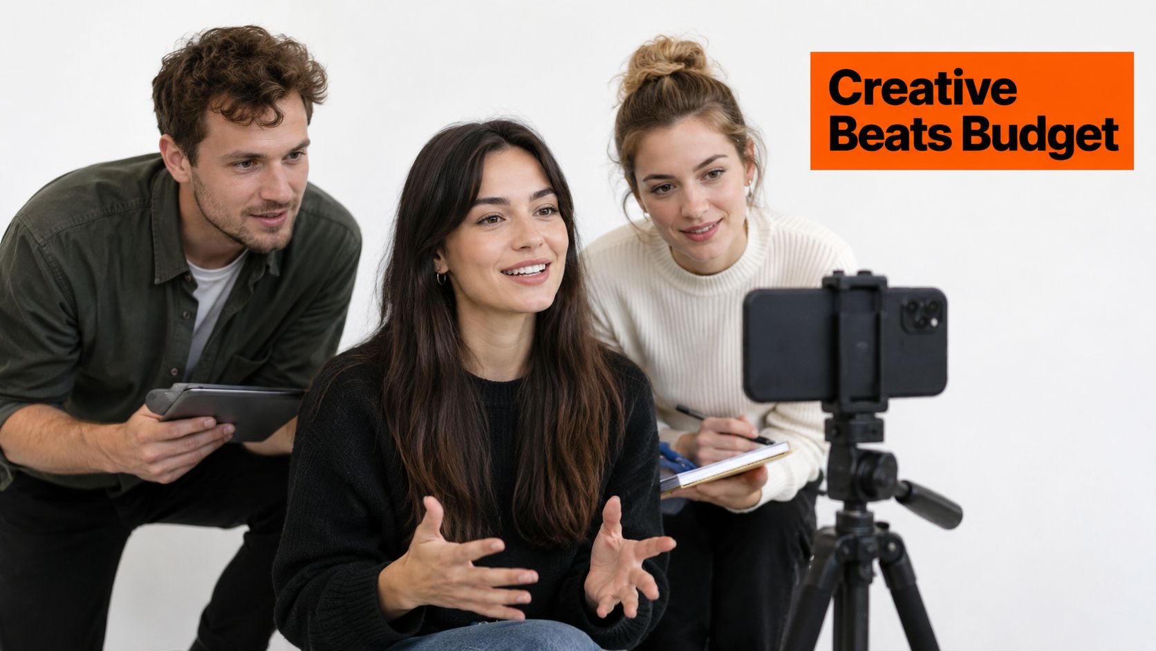 A team of three professionals collaborating and filming content for a creative video project using a smartphone.