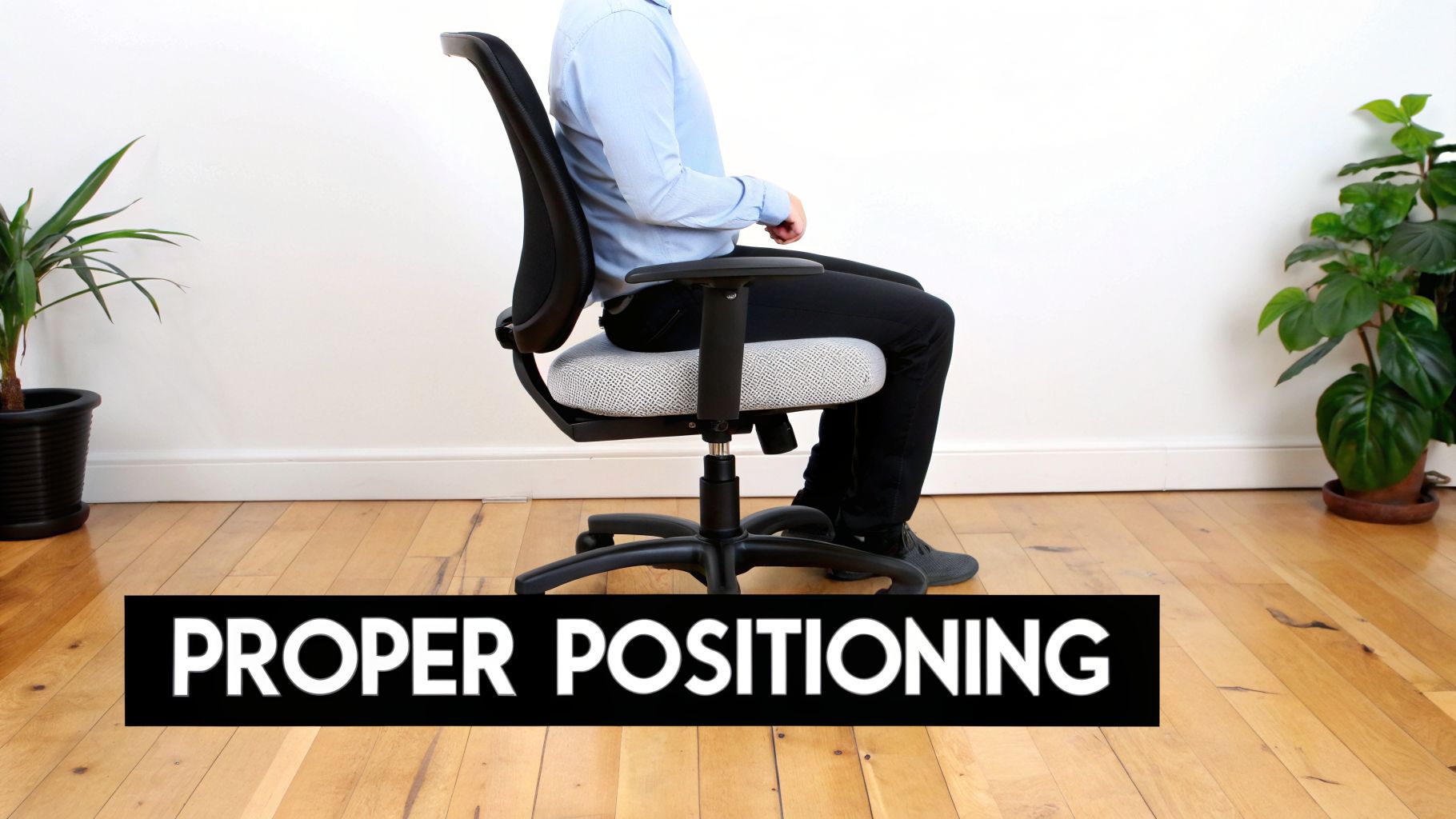 A person sits on an office chair with a grey seat cushion, demonstrating proper ergonomic posture.