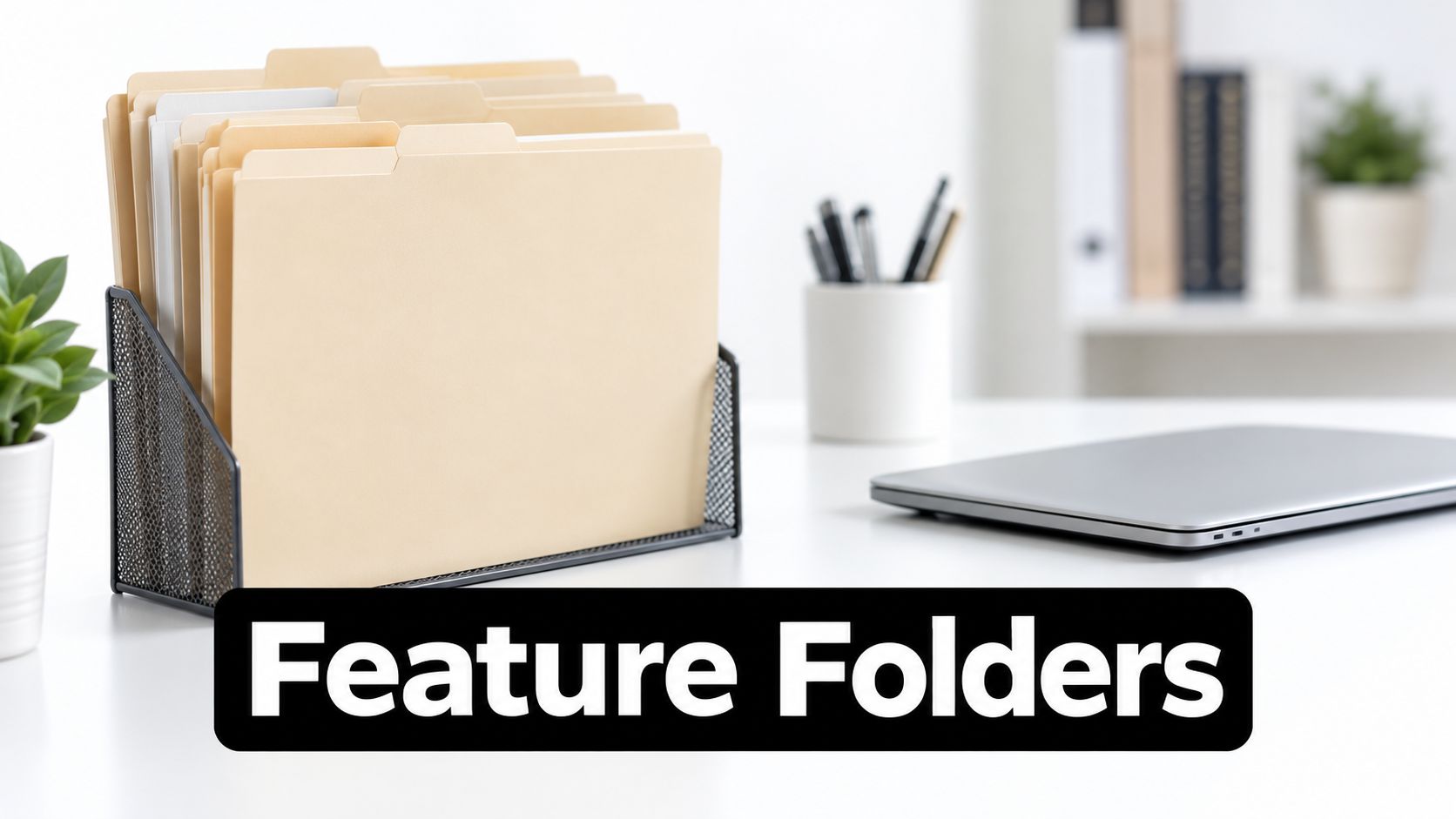 A mesh metal organizer filled with manila folders sits on a clean white desk near a laptop.