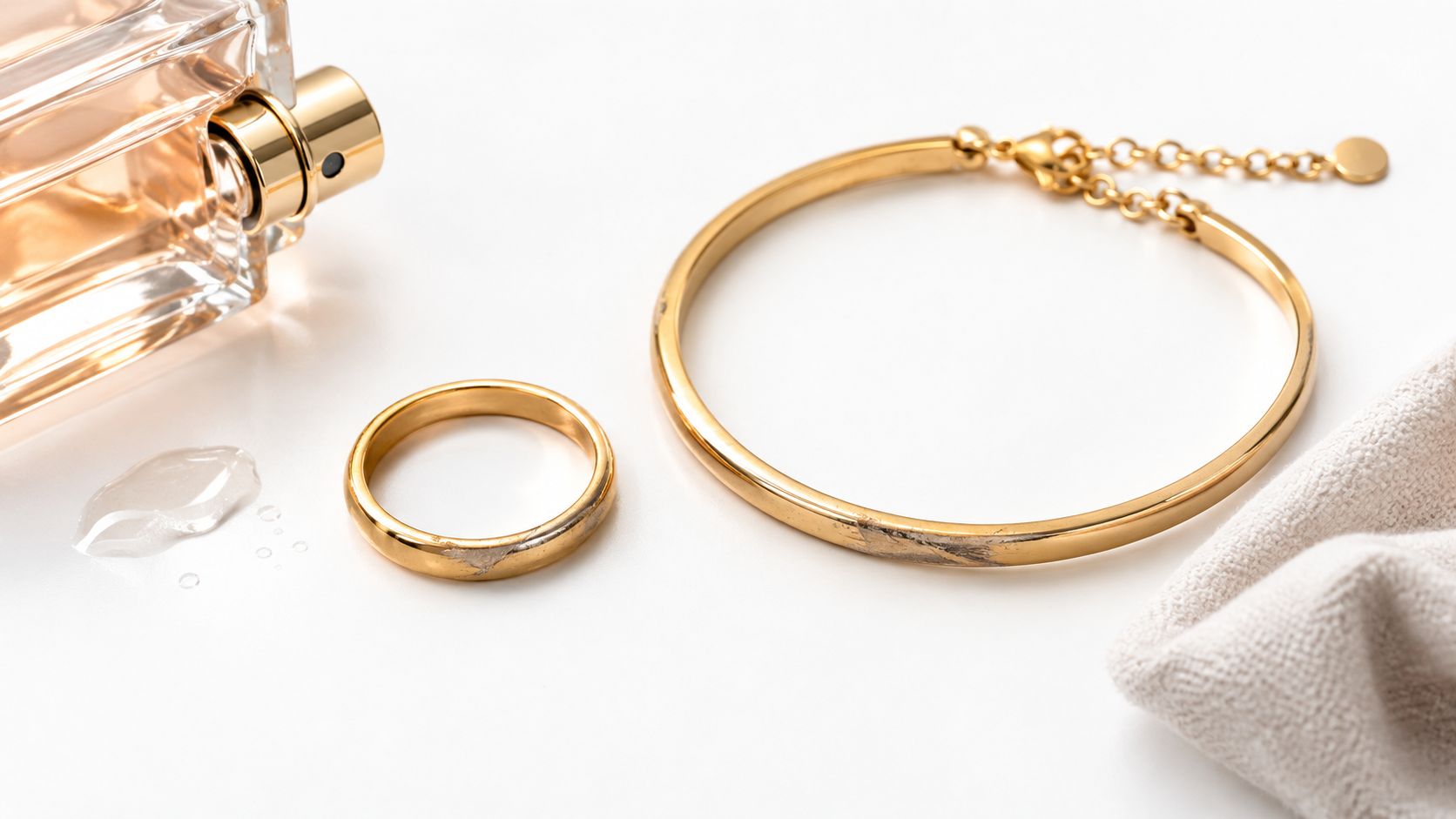 A worn gold ring and bracelet next to a bottle of perfume and a cleaning cloth
