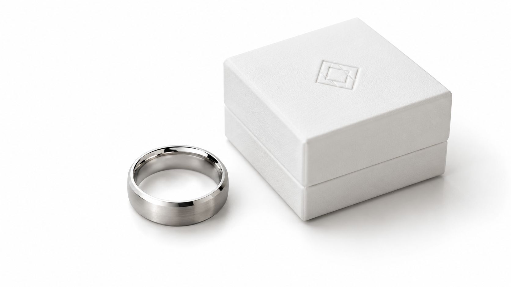 Silver-tone ring beside a white square jewelry box.
