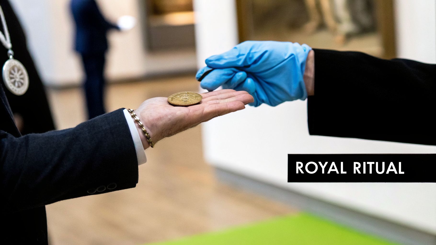 A gloved hand reaches for a gold coin held by another hand in a suit, during a royal ritual.