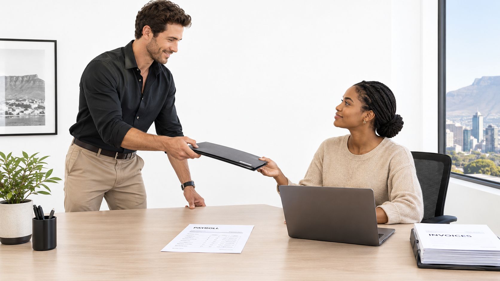 A professional man handing a folder to a female colleague sitting at a desk in an office.