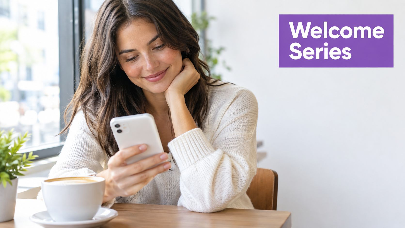 A smiling young woman in a white sweater looking at her smartphone while sitting in a cafe.