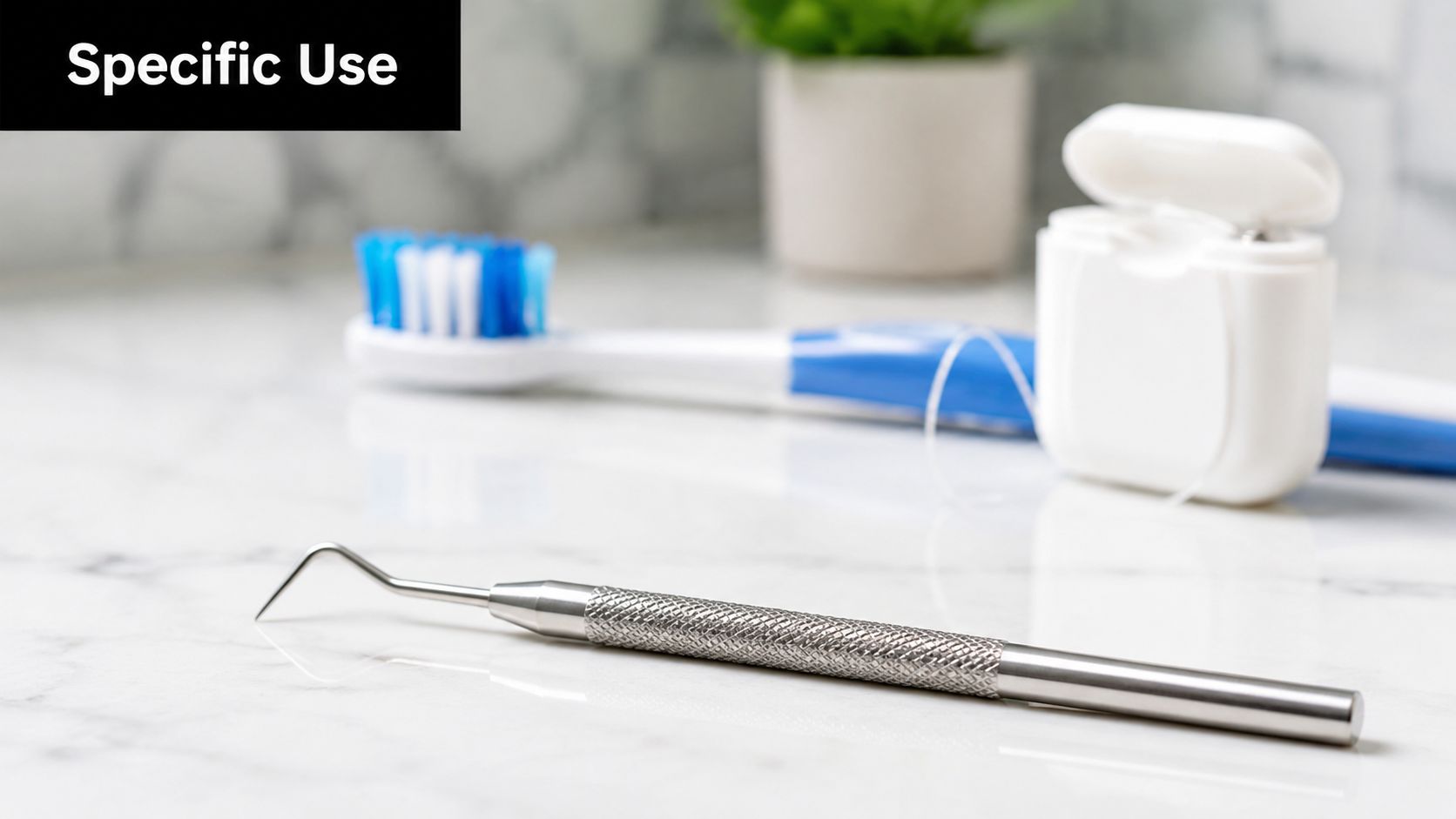 A professional dental pick lying on a marble countertop next to a manual toothbrush and dental floss.