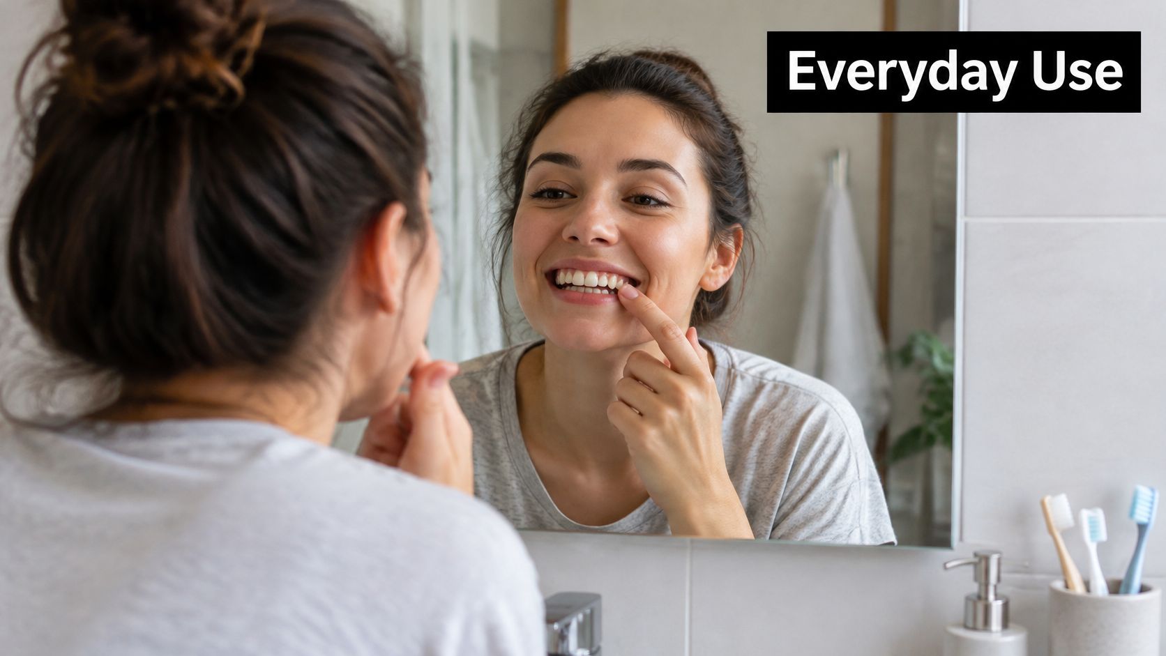 A woman looks in the bathroom mirror while touching her teeth to inspect their whiteness.